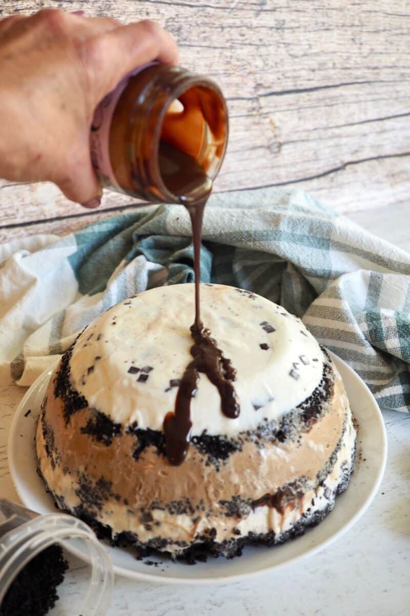 Pouring fudge on ice cream cake. 