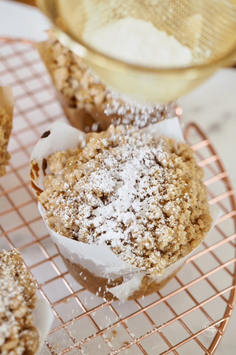 Dusting top of cooled pumpkin muffin with powdered sugar.