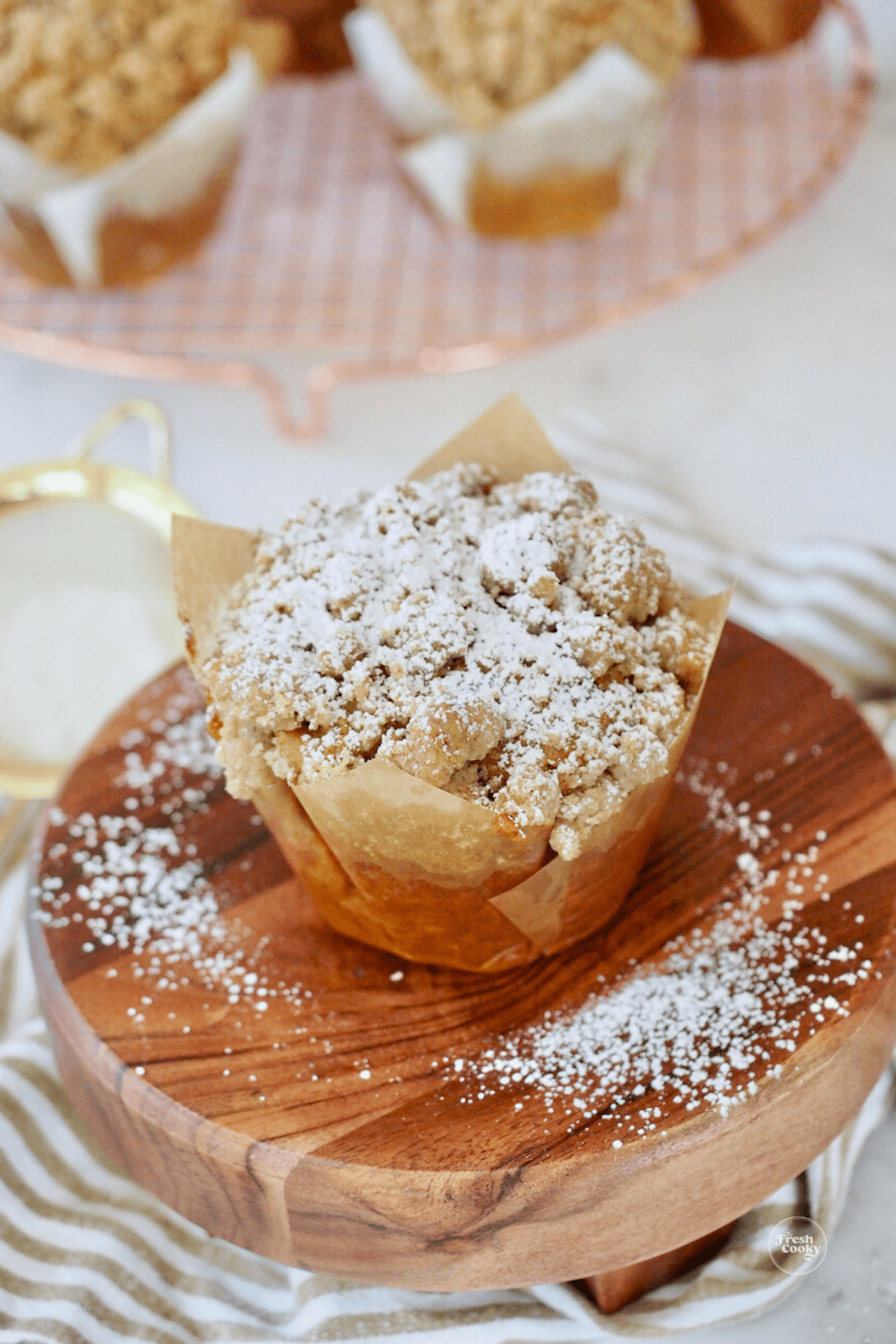 Panera pumpkin muffin on wooden pedestal, sprinkled with powdered sugar.