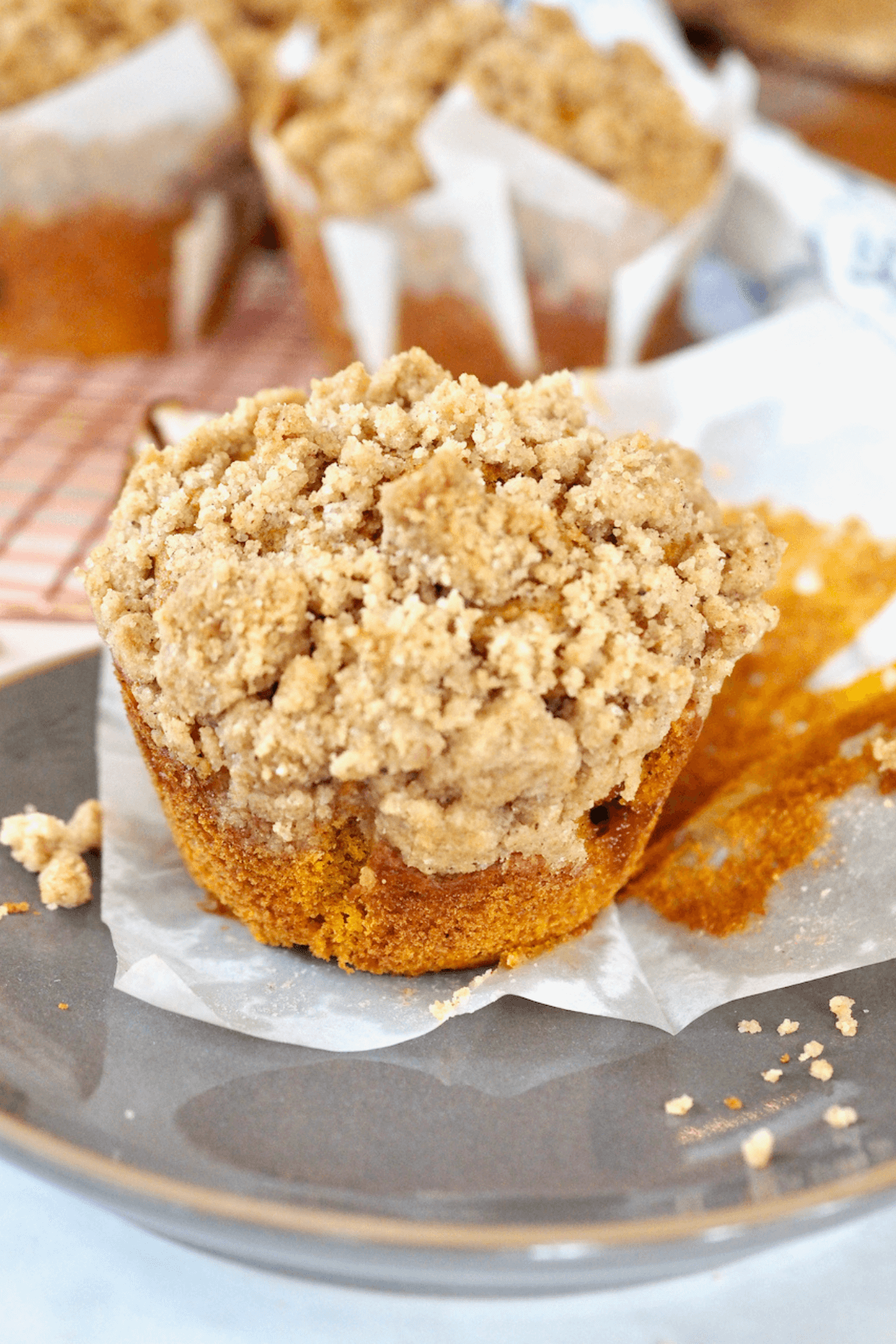 Jumbo Pumpkin muffin on plate with streusel crumbs on top.