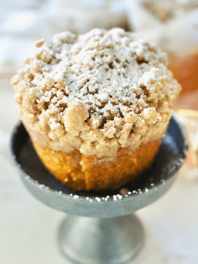 Panera pumpkin muffin on mini pedestal sprinkled with powdered sugar with generous crumb topping.