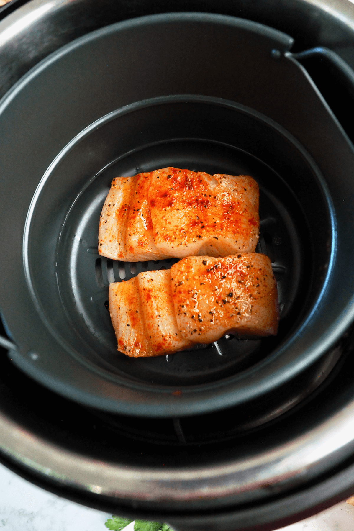 Halibut filets placed into basket of air fryer. 