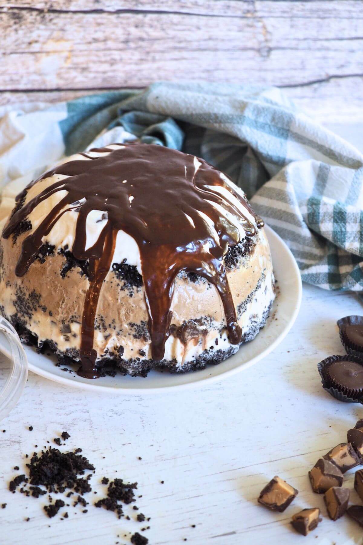 Whole mud pie recipe on plate topped with fudge.