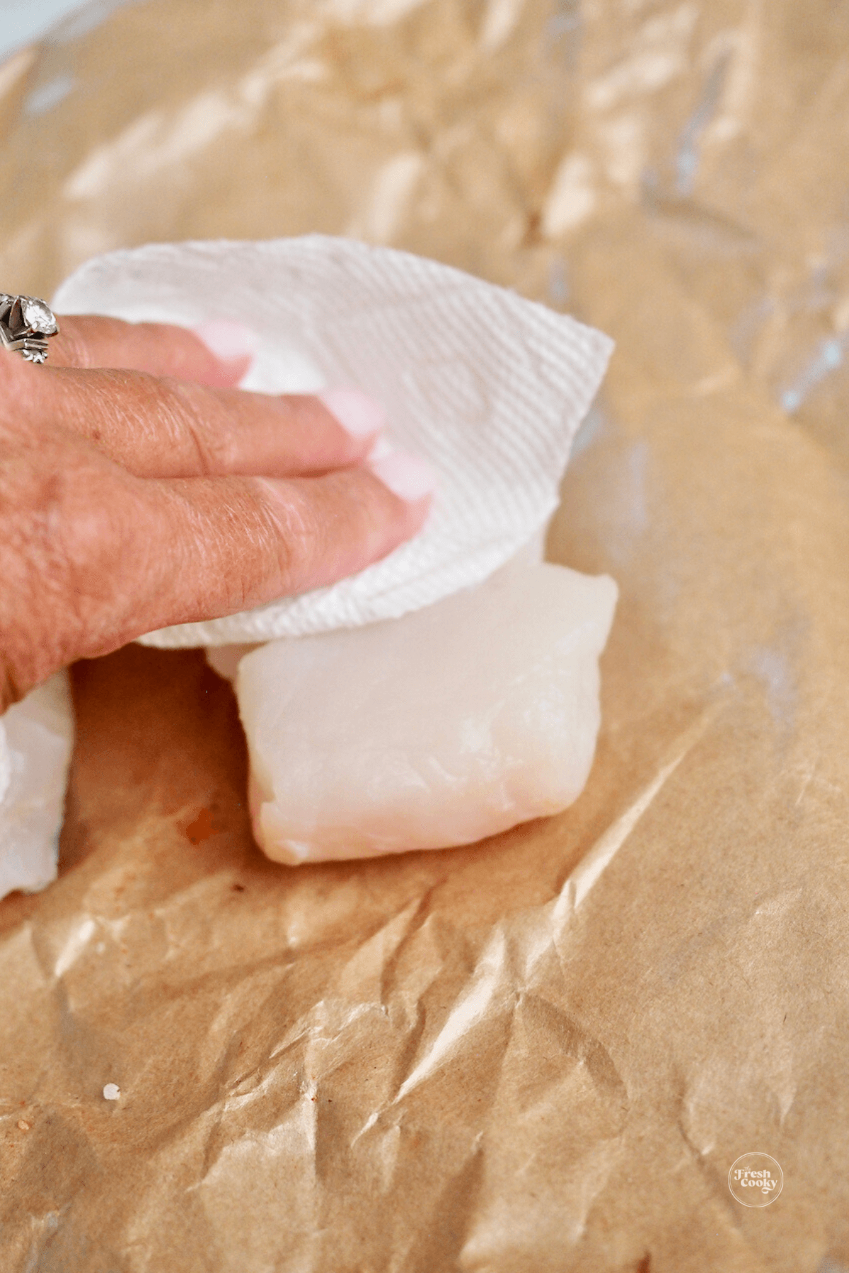 Hand patting dry halibut filet with paper towel. 