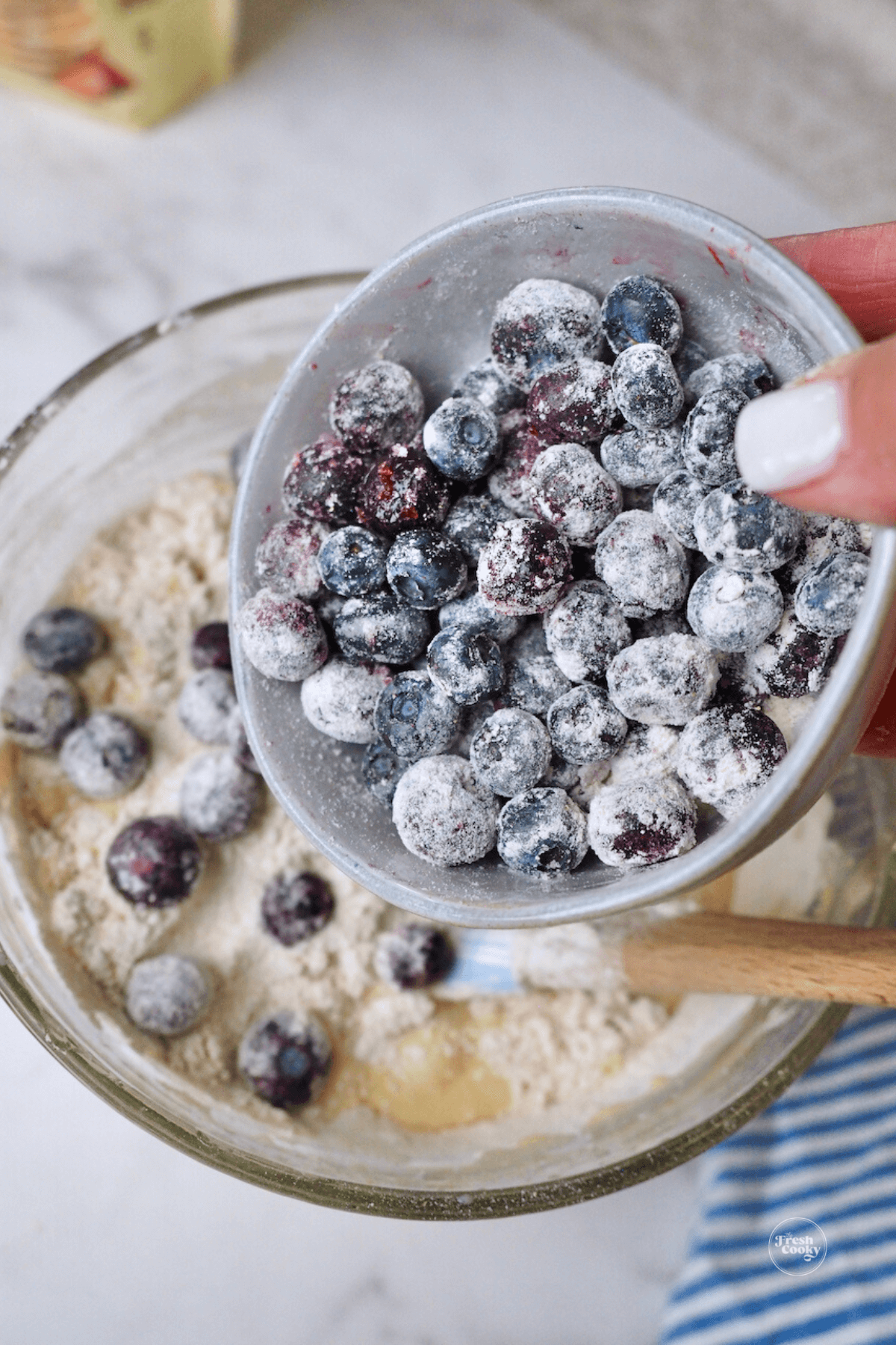 Pouring dusted blueberries into wet batter. 