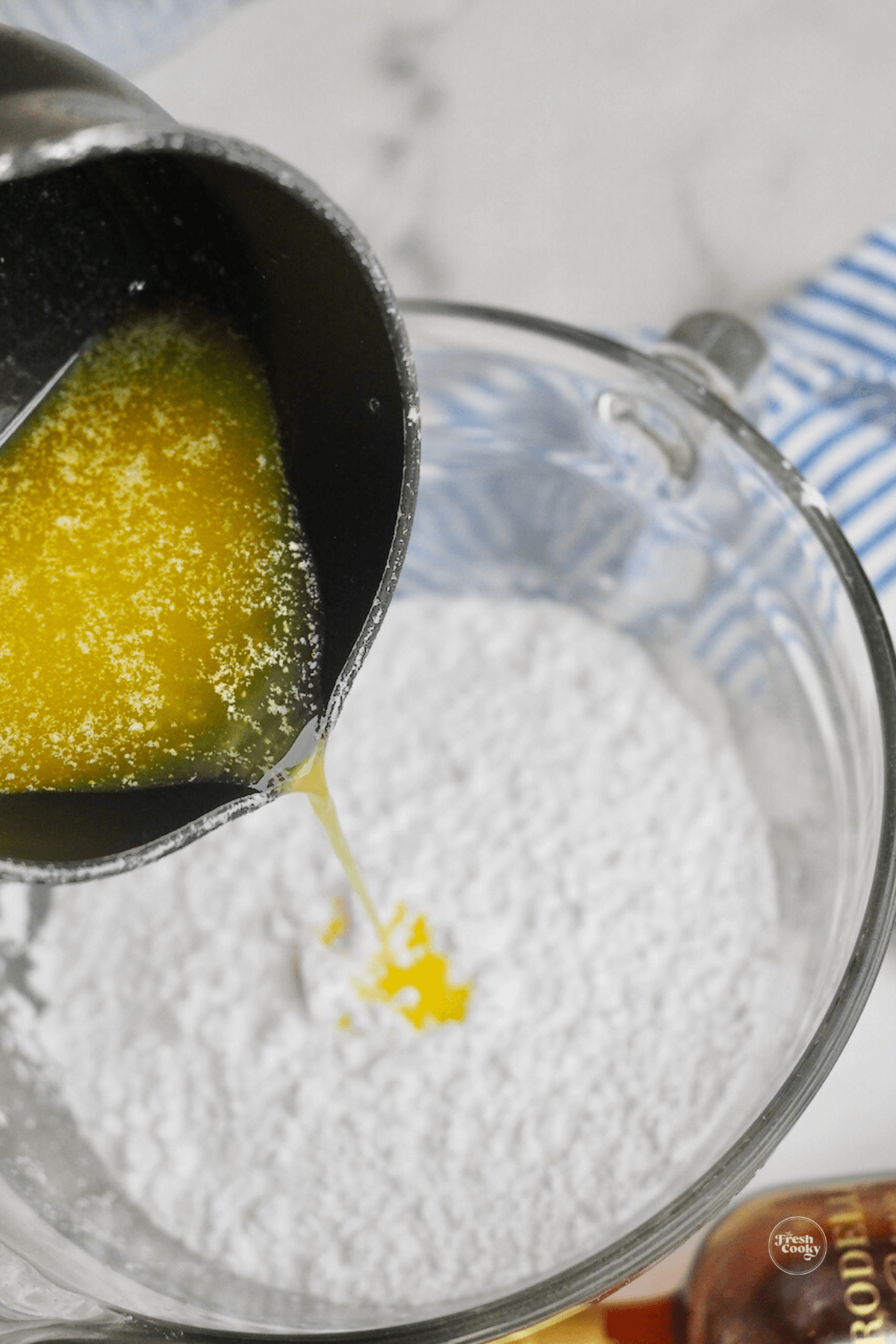 Pouring melted butter into powdered sugar. 