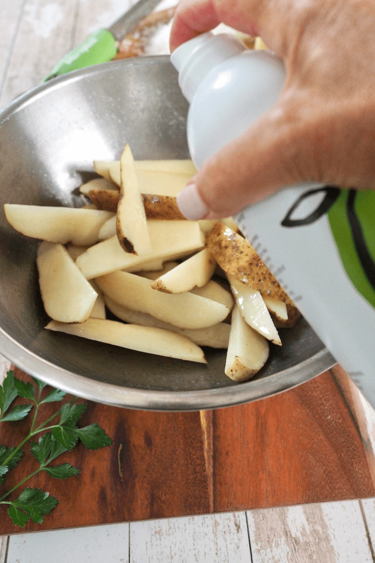 Spraying fries with avocado oil.