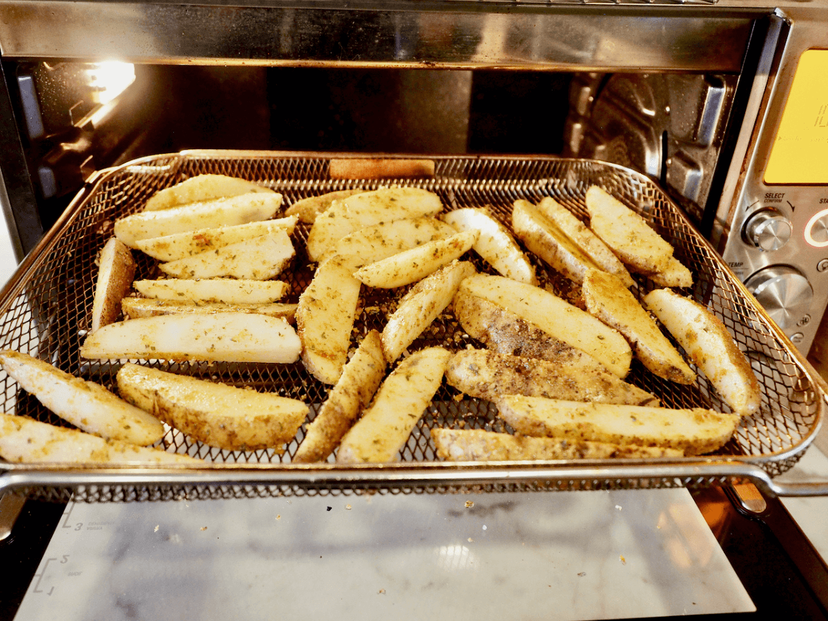 Steak fries on basket of large air fryer.
