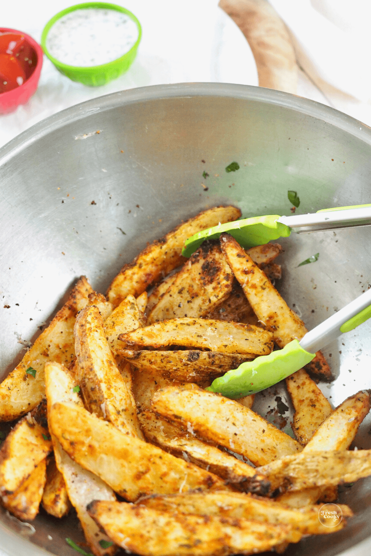 Cooked steak fries removed and placed in bowl tossing with tongs.