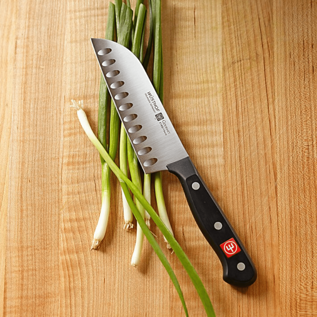 Wusthof Santoku Knife with scallions on cutting board.