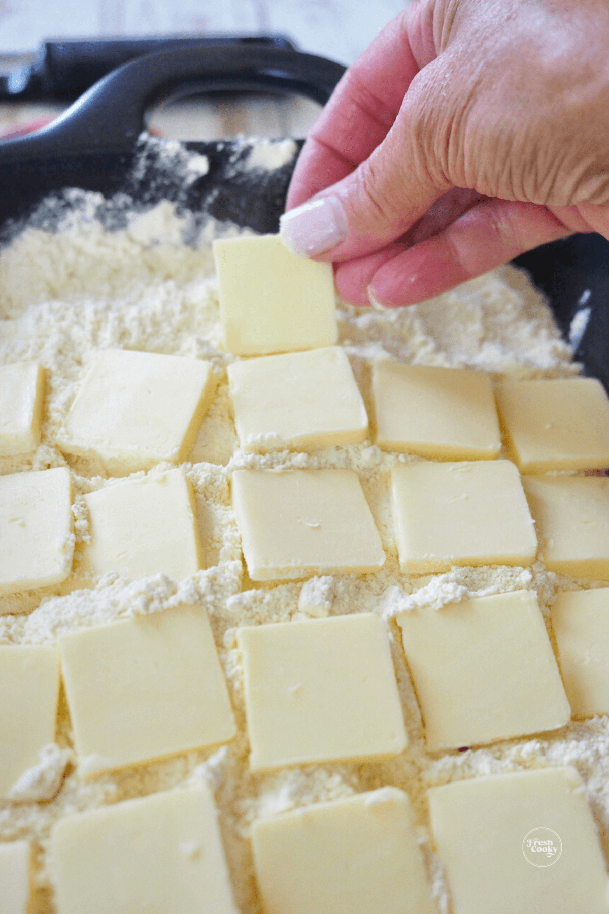 Hand placing butter pats on top of dump cake. 