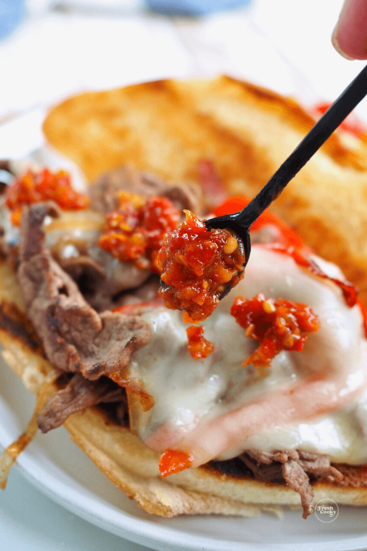 Adding hots to steak sandwich.