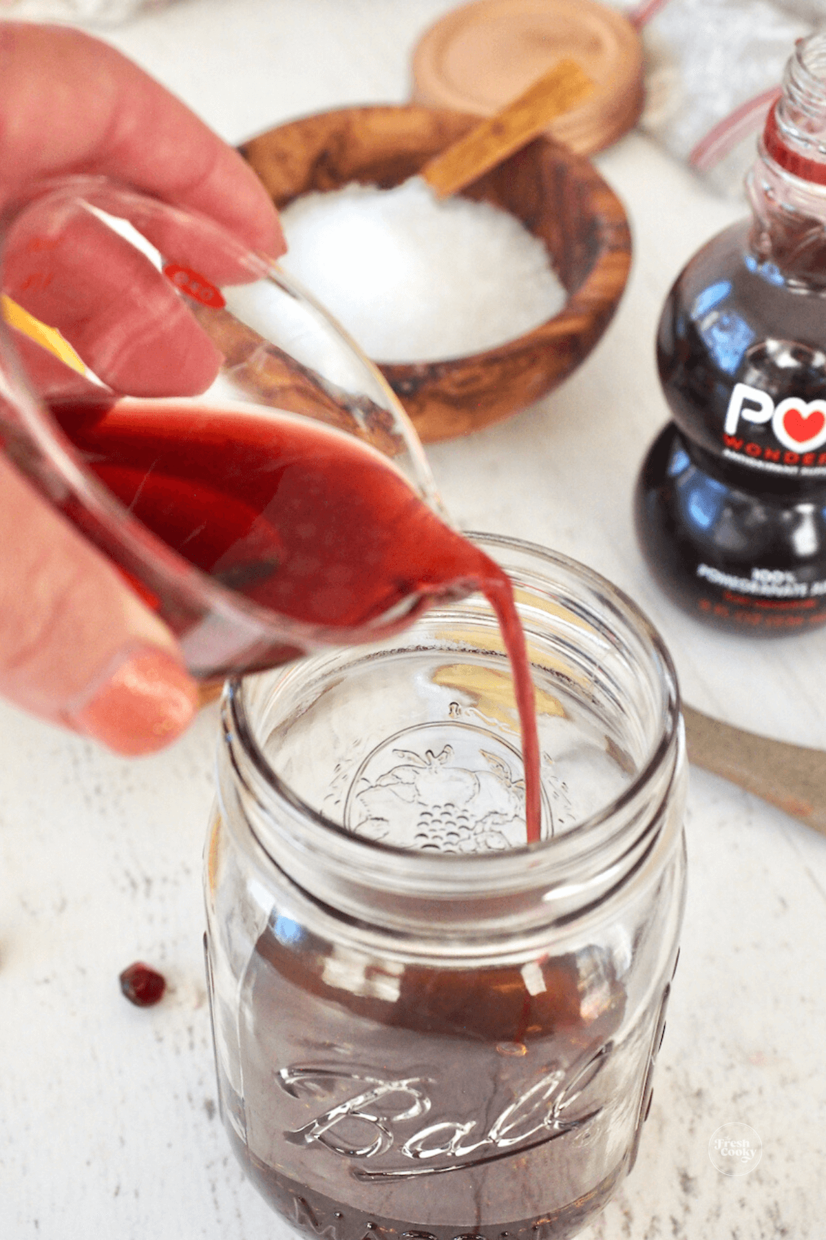 Adding pomegranate juice to mason jar.