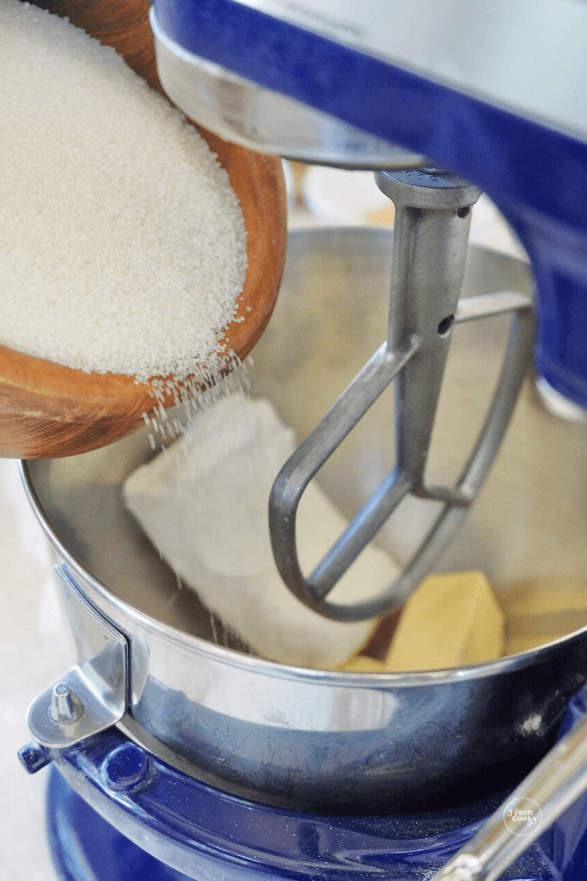 Pouring sugar into mixing bowl with butter and cream cheese.