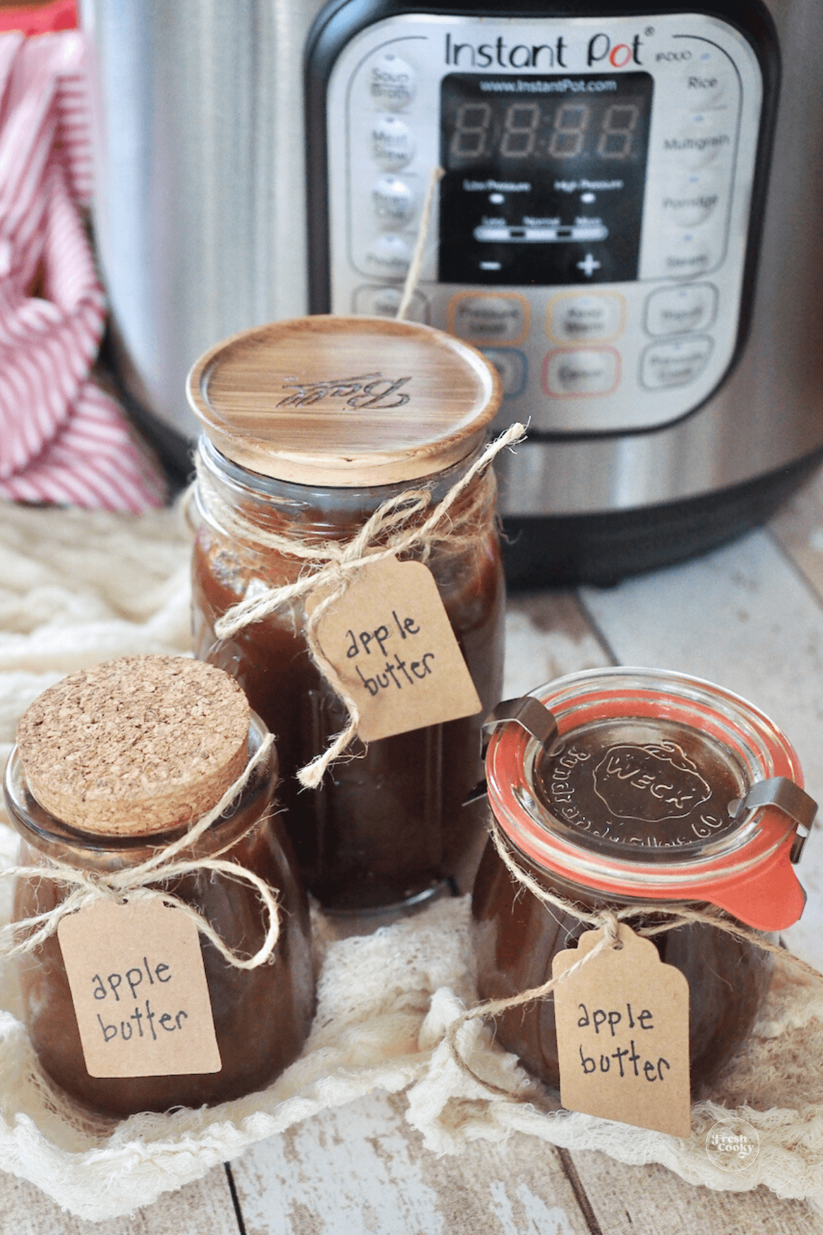 Apple butter in jars with labels and instant pot in background.
