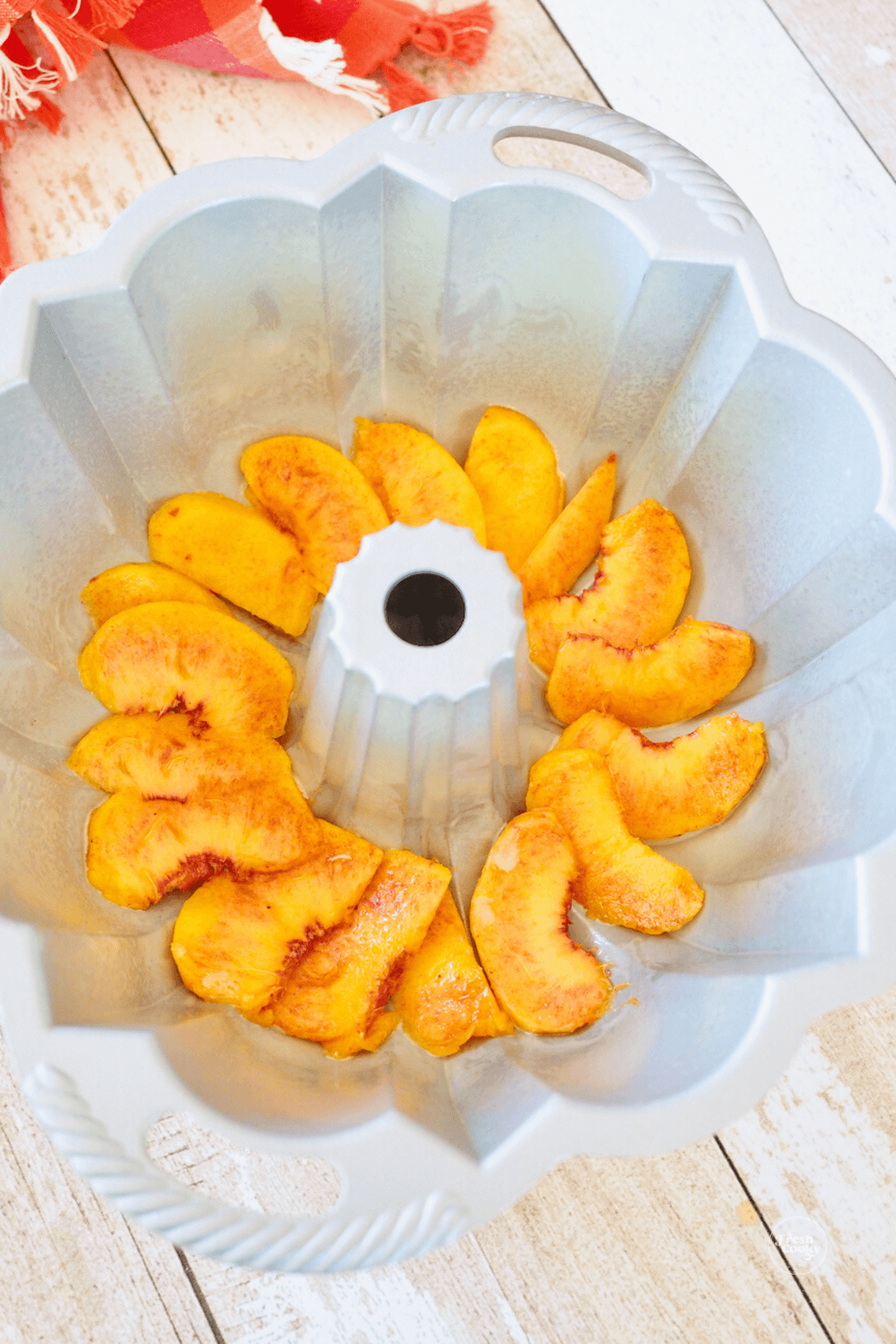 Sliced peaches laid in the bottom of a bundt pan. 