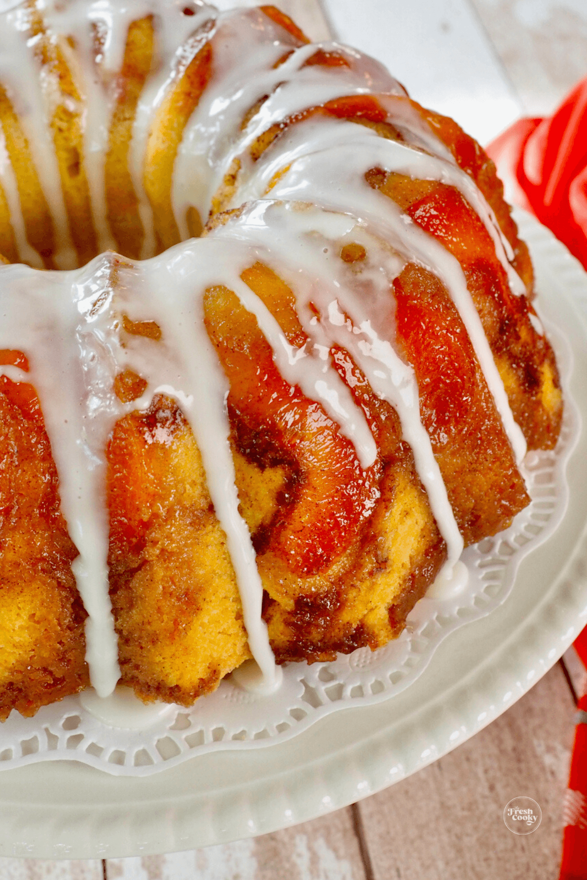 Peach cobbler cake on pedestal with drizzles of glaze.