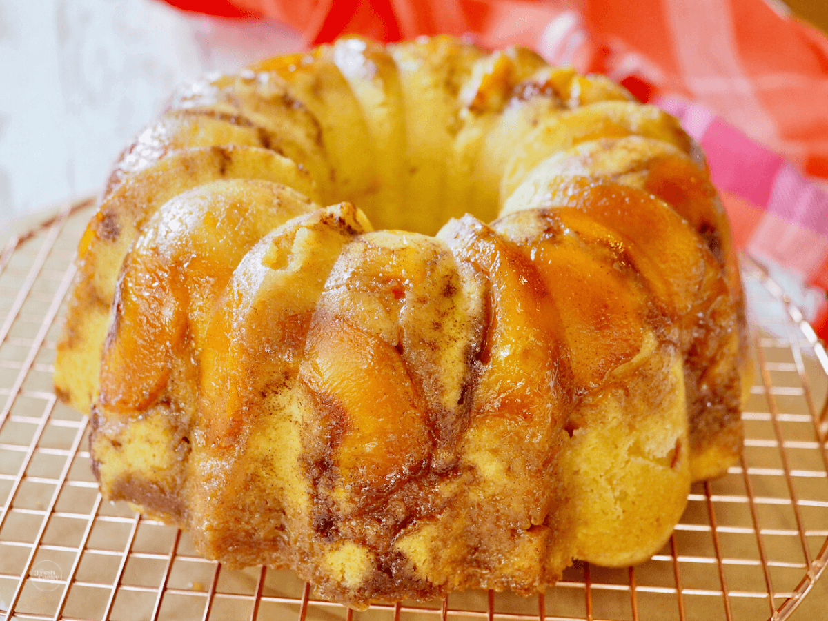 Bundt cake with sliced peaches imbedded in cake on cooling rack.