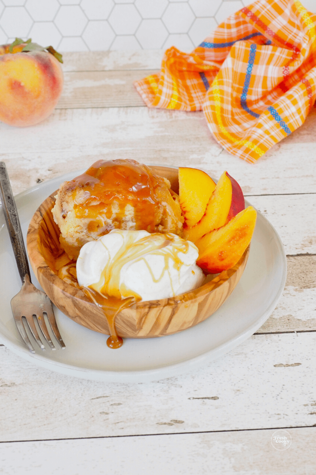 Peach cobbler pound cake in bowl with ice cream with caramel.