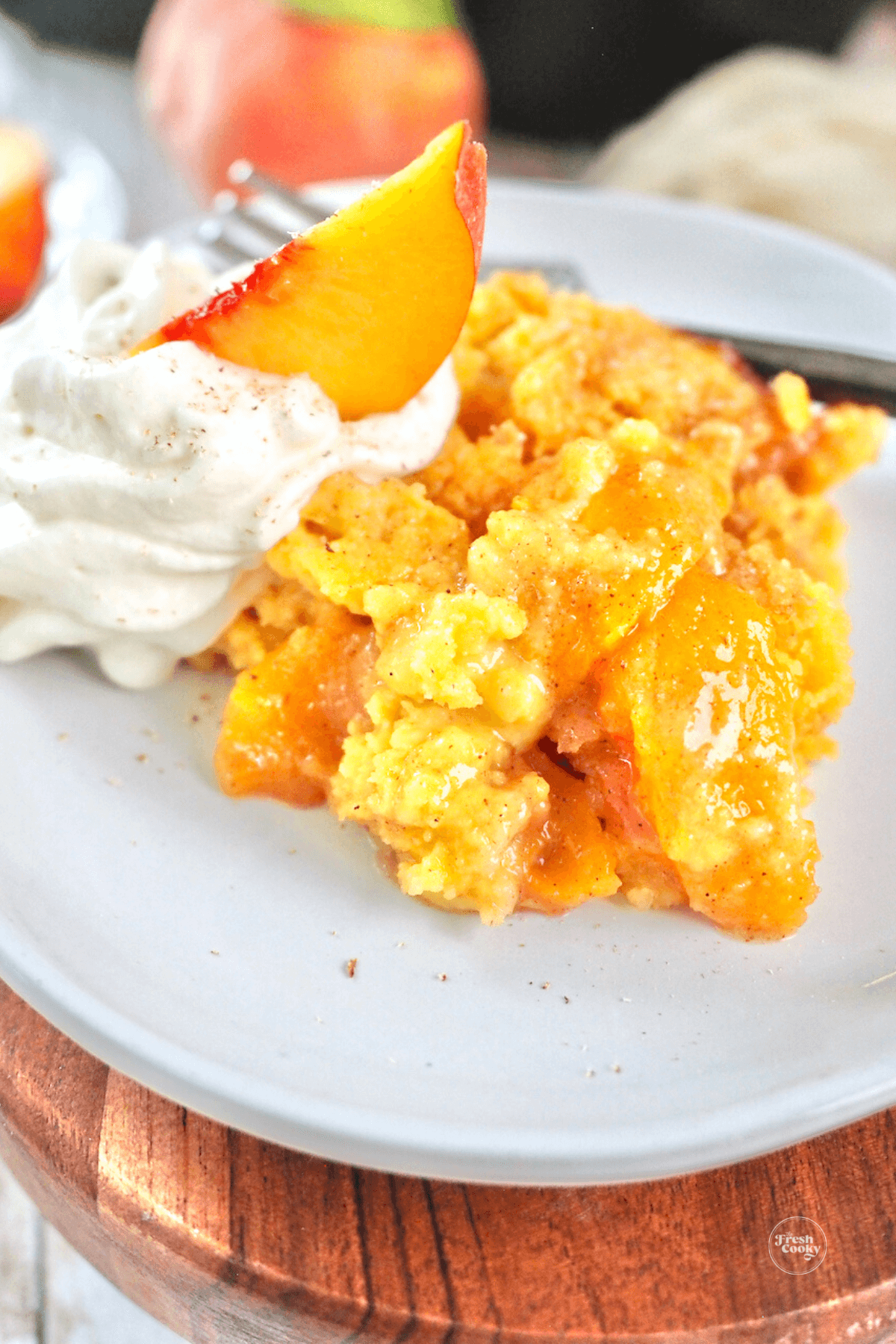 Peach cobbler served with whipped cream and slice of fresh peach.