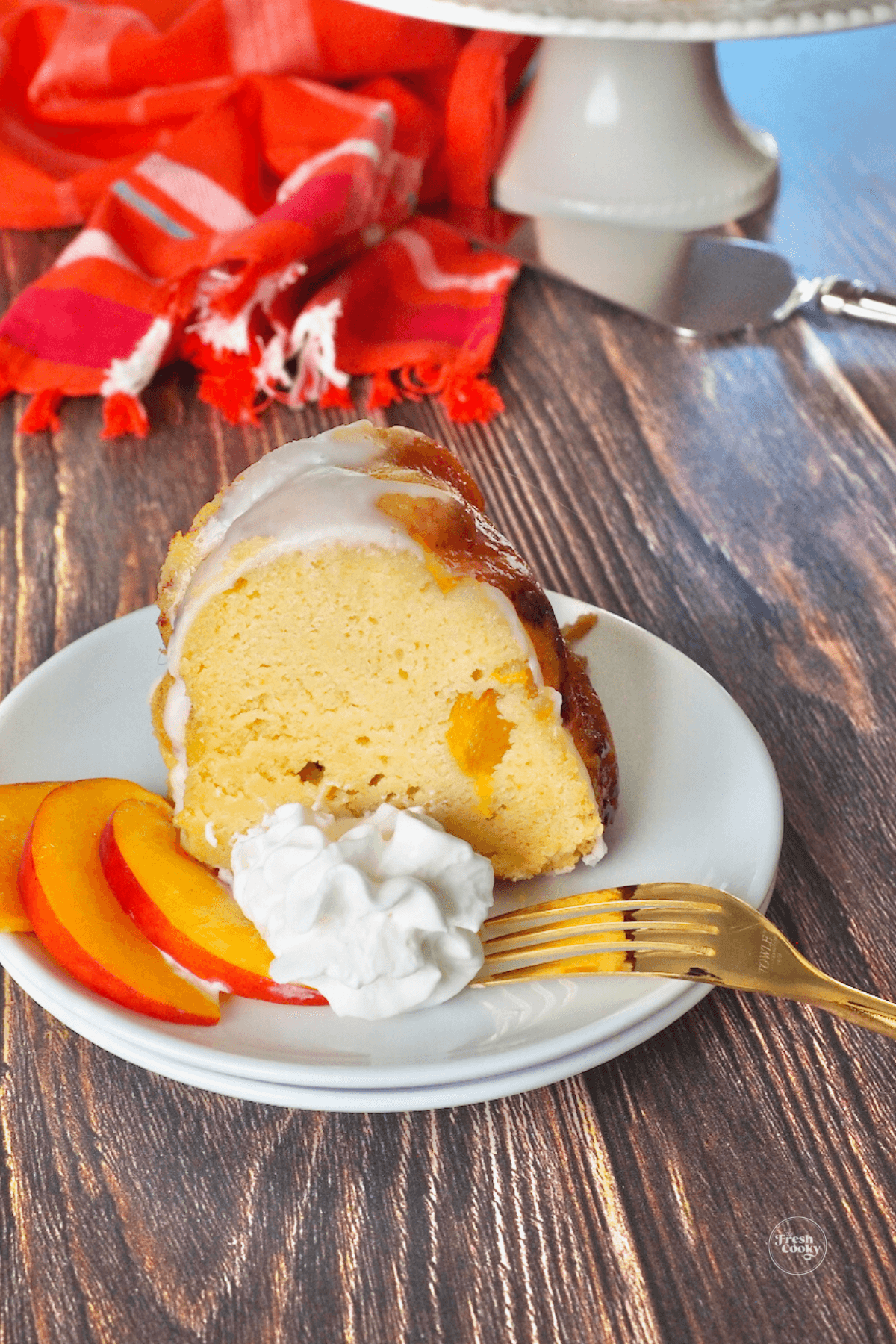 Slice of peach cake with bourbon whipped cream with fresh peaches. 