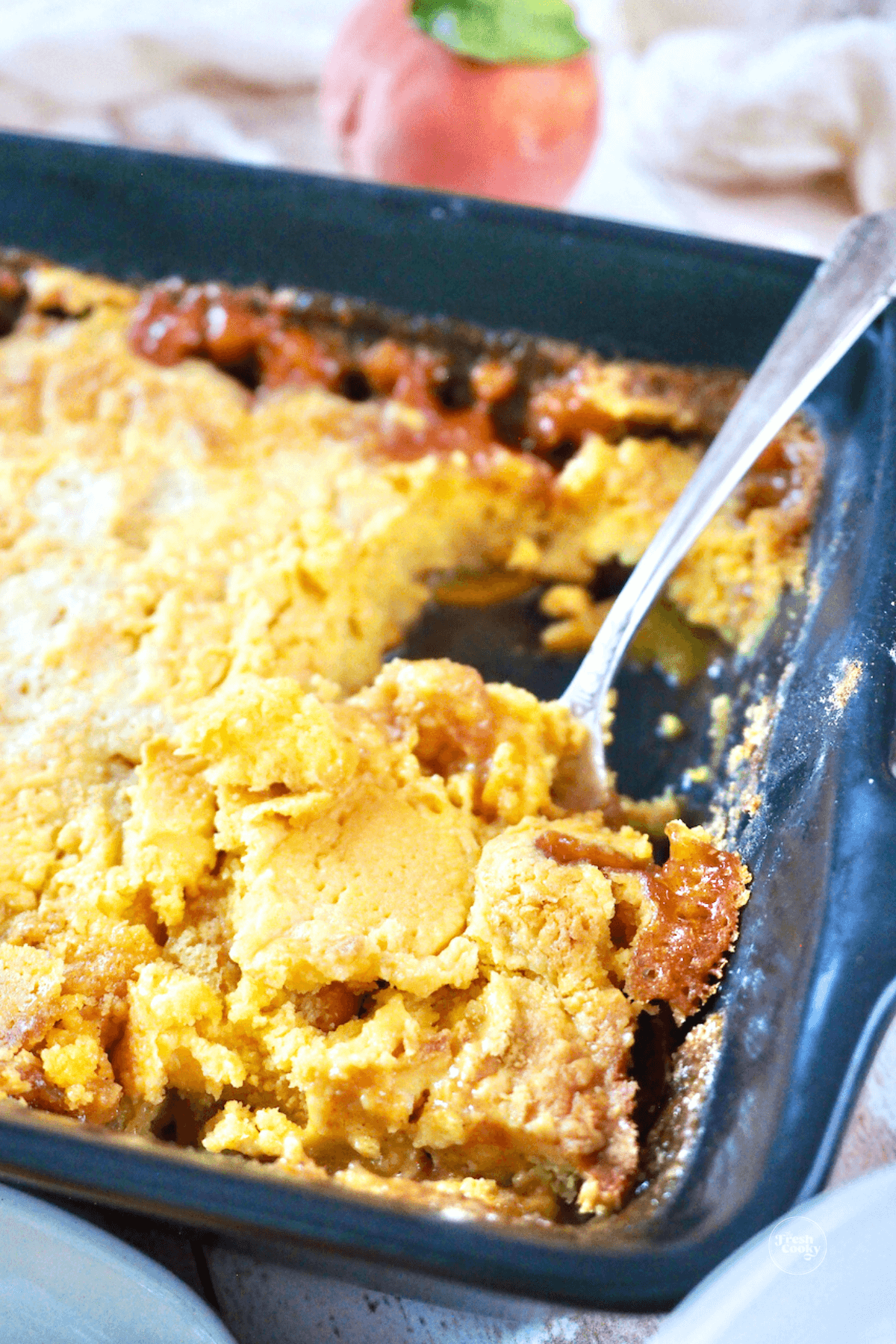 Spoon serving peach dump cake.