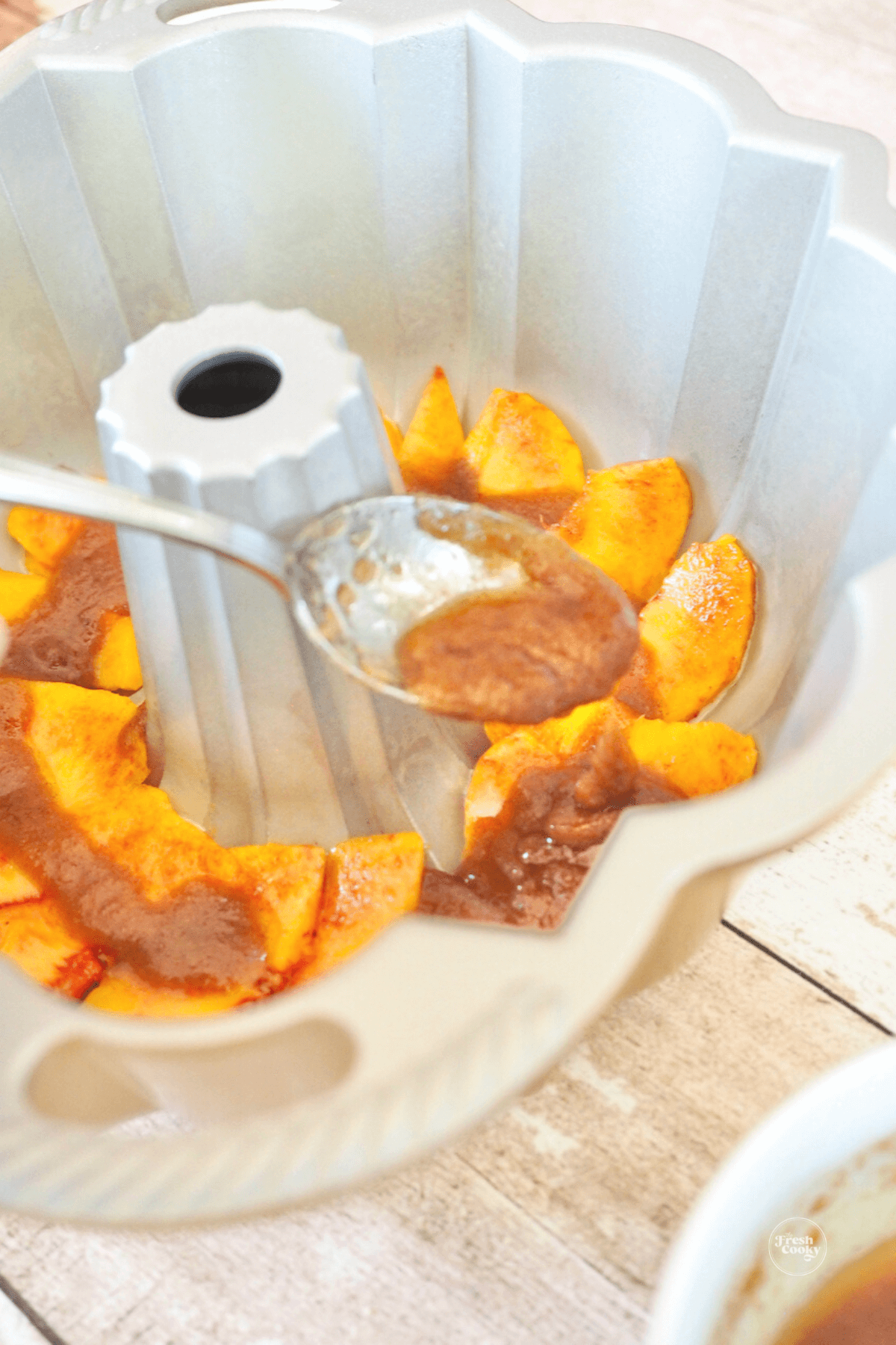 Adding buttery brown sugar mixture over top of peaches. 