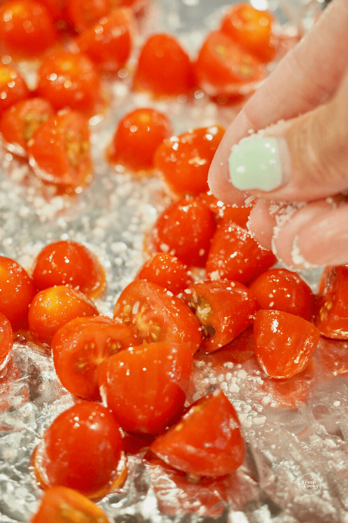 Sliced grape or cherry tomatoes on foil lined tray drizzled with olive oil and sprinkled with sea salt.