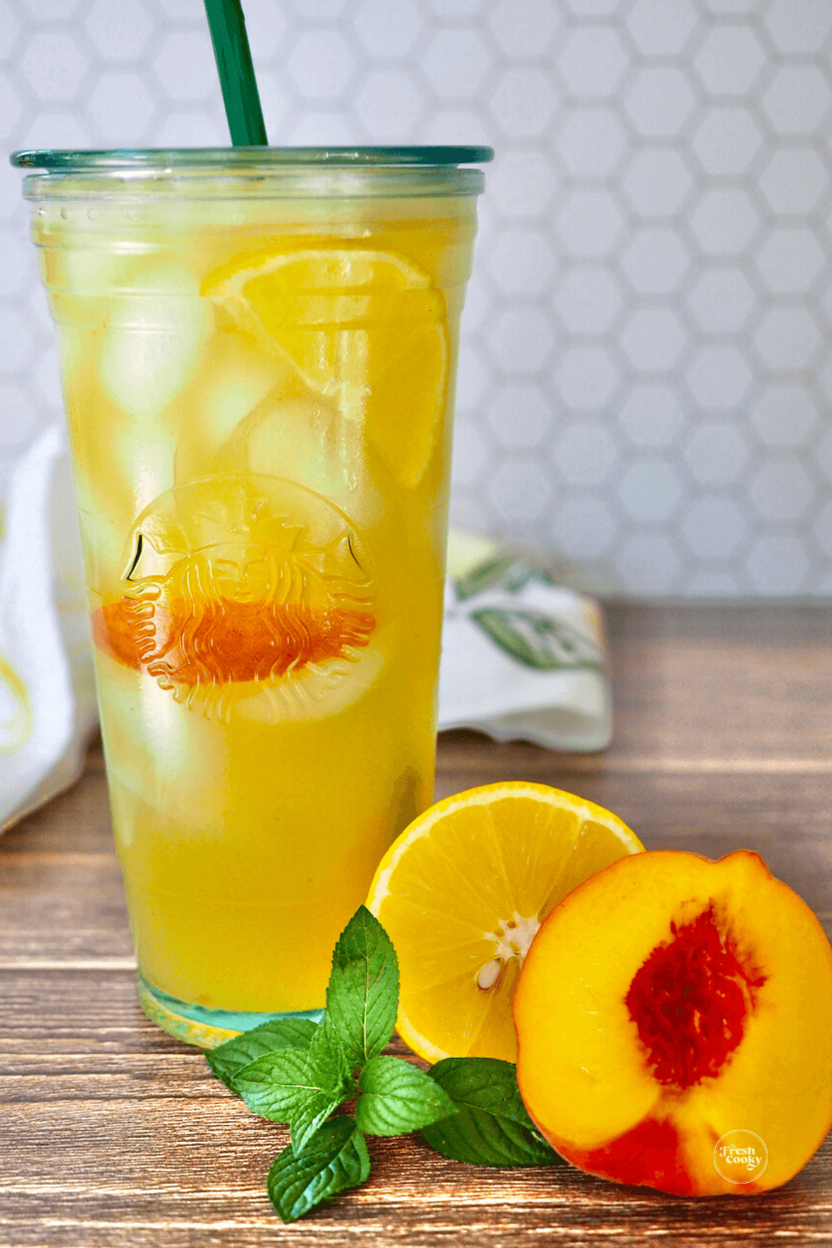 Iced peach green tea in a Starbucks clear class cup with lid and straw.