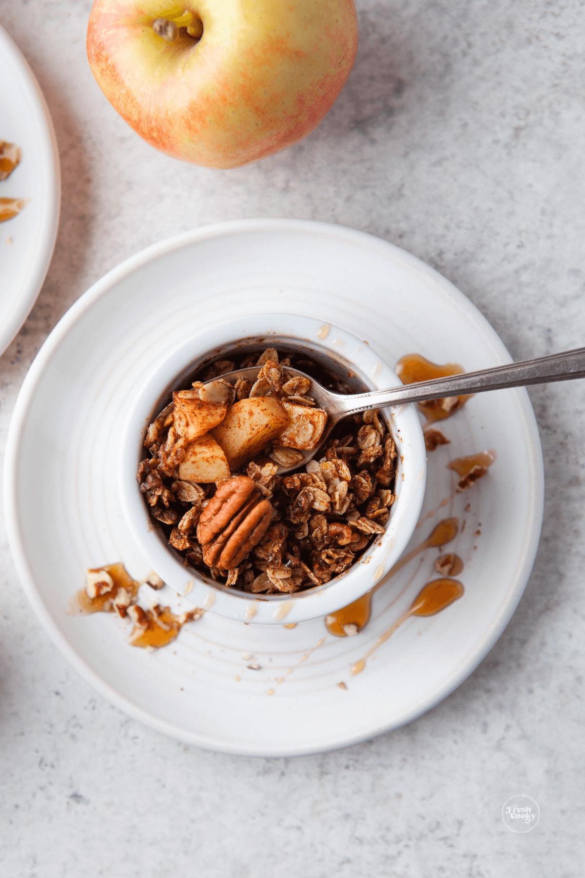 Apple crisp serving on a plate that is drizzled with maple syrup.