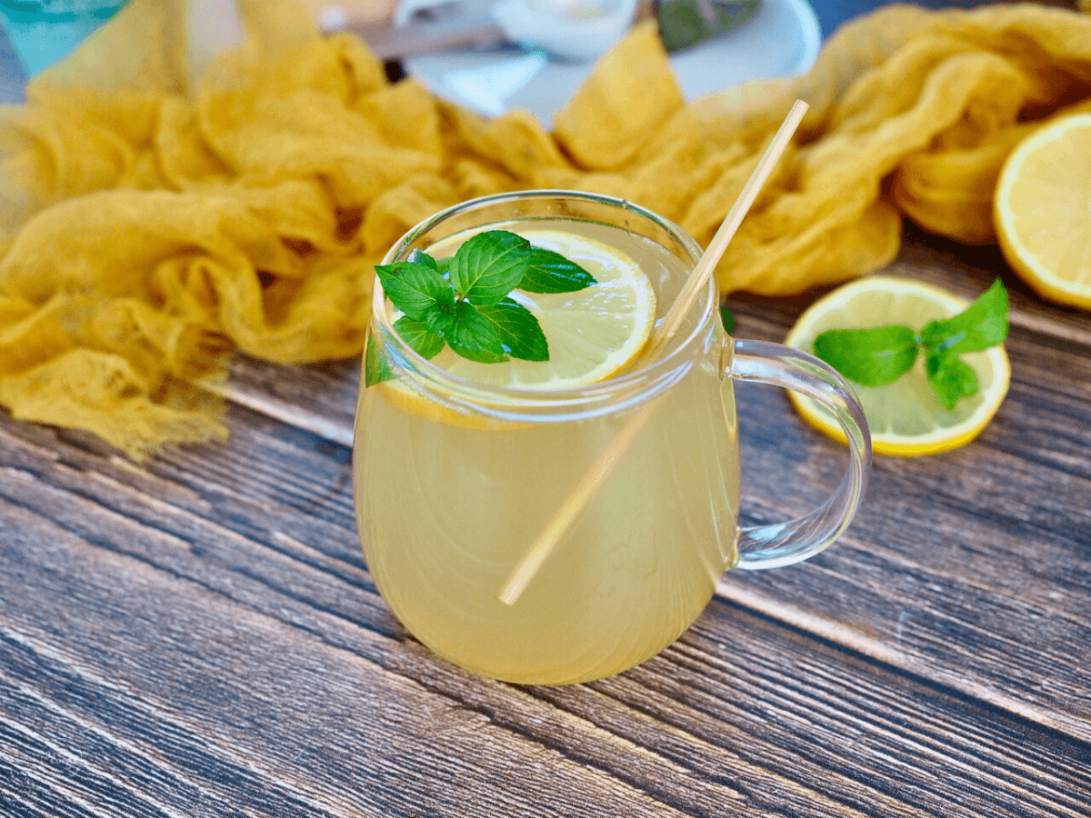 Medicine ball tea in a clear glass mug with lemon slices and fresh mint.