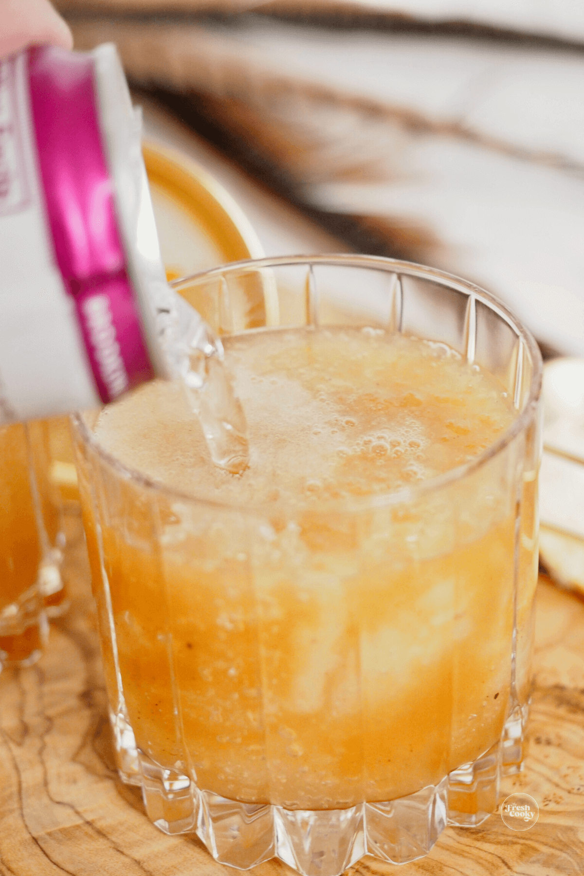 Pouring ginger beer on top of apple cider cocktail.
