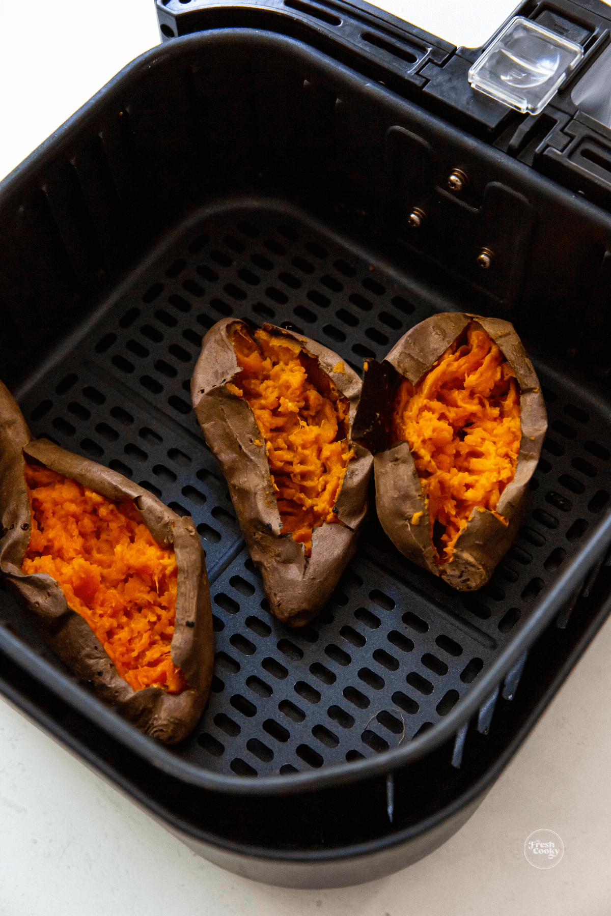 Split open sweet potatoes in air fryer basket. 