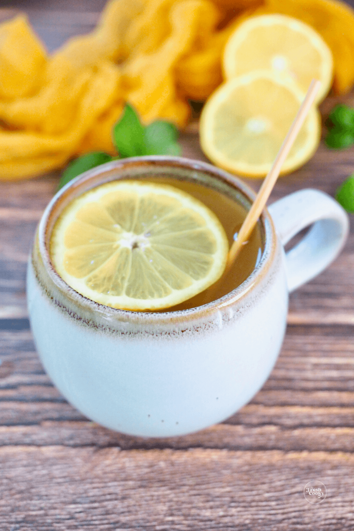 Ceramic mug filled with Copycat Starbucks Medicine Tea ball tea with a wheel of lemon.