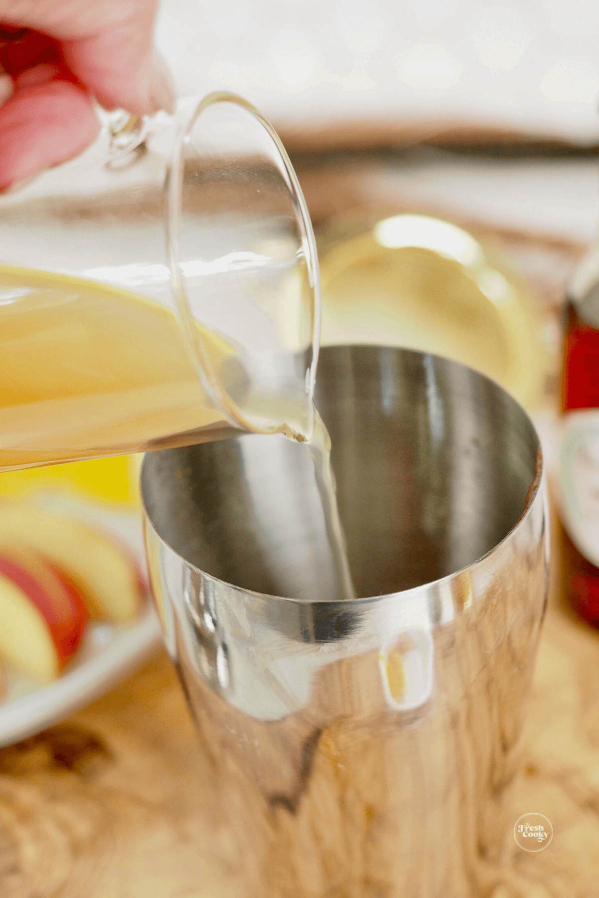 Pouring apple cider into cocktail shaker. 