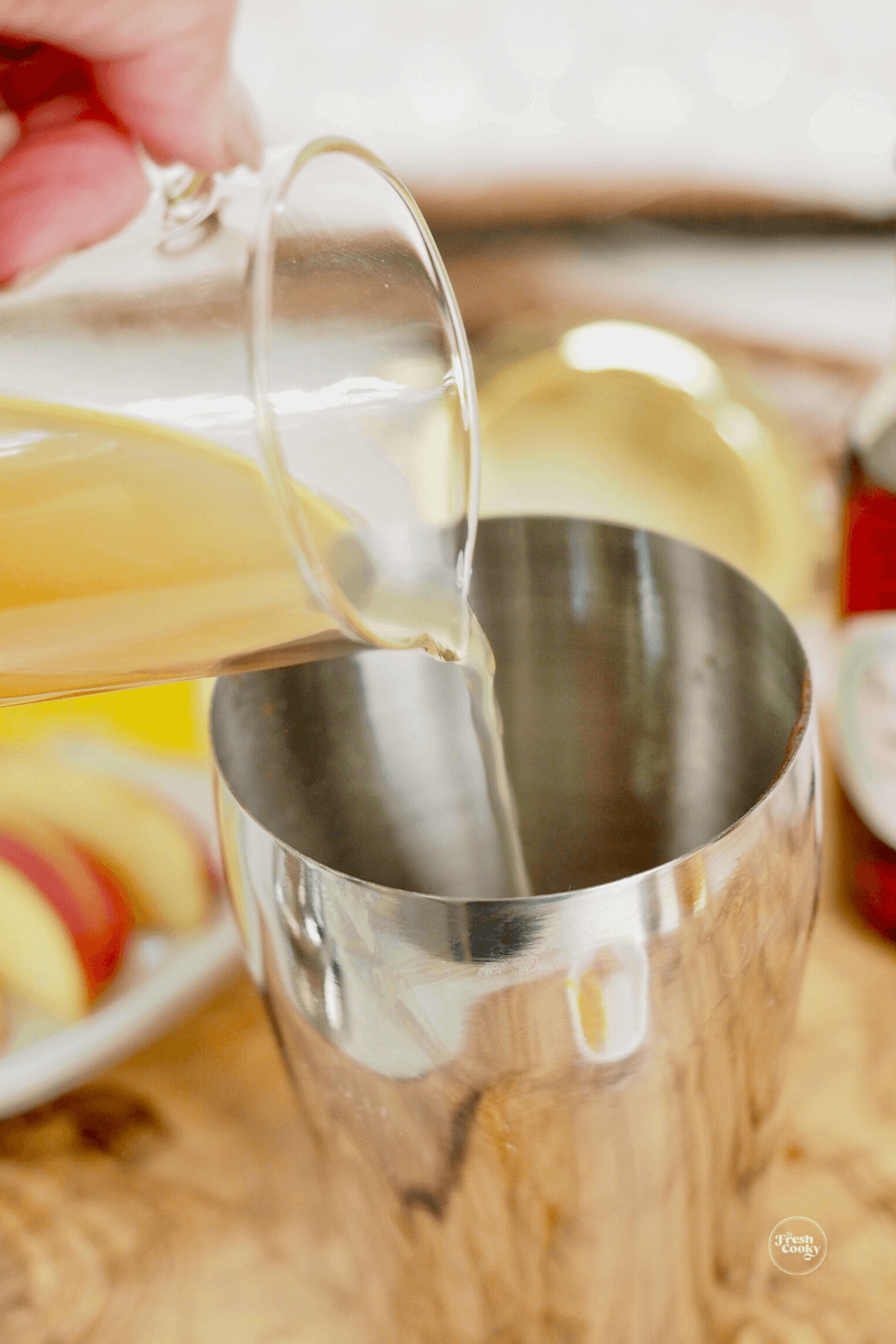 Pouring apple cider into cocktail shaker.