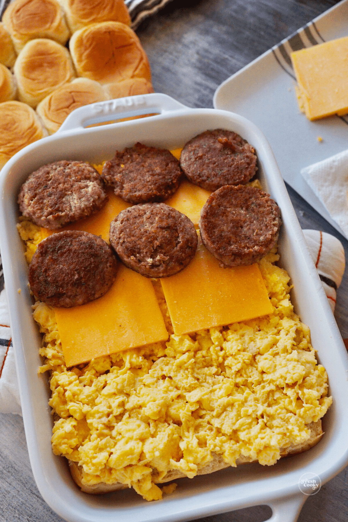Layers showing eggs, cheese and sausage on breakfast sliders. 