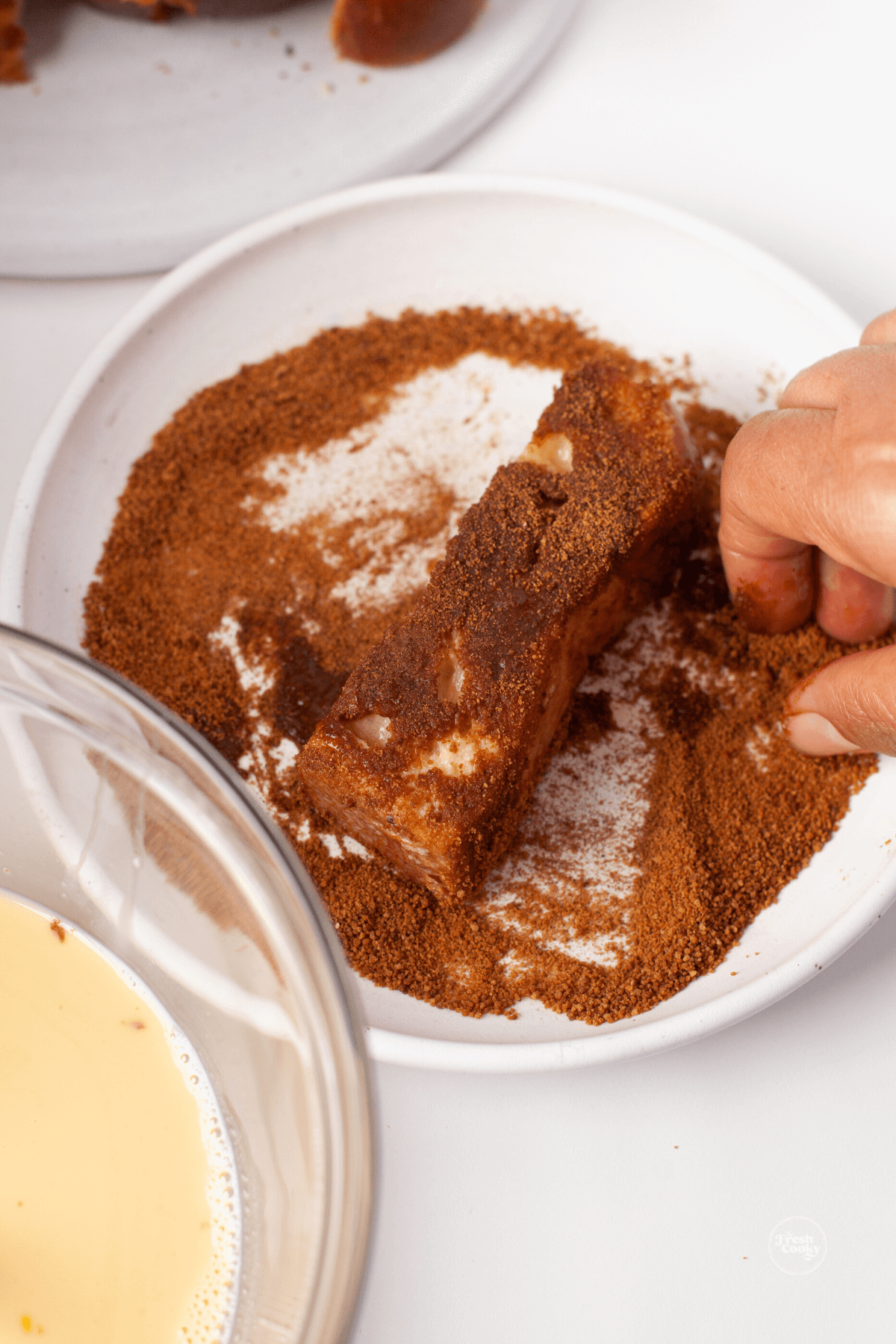 Covering all sides of french toast stick in cinnamon sugar mixture. 