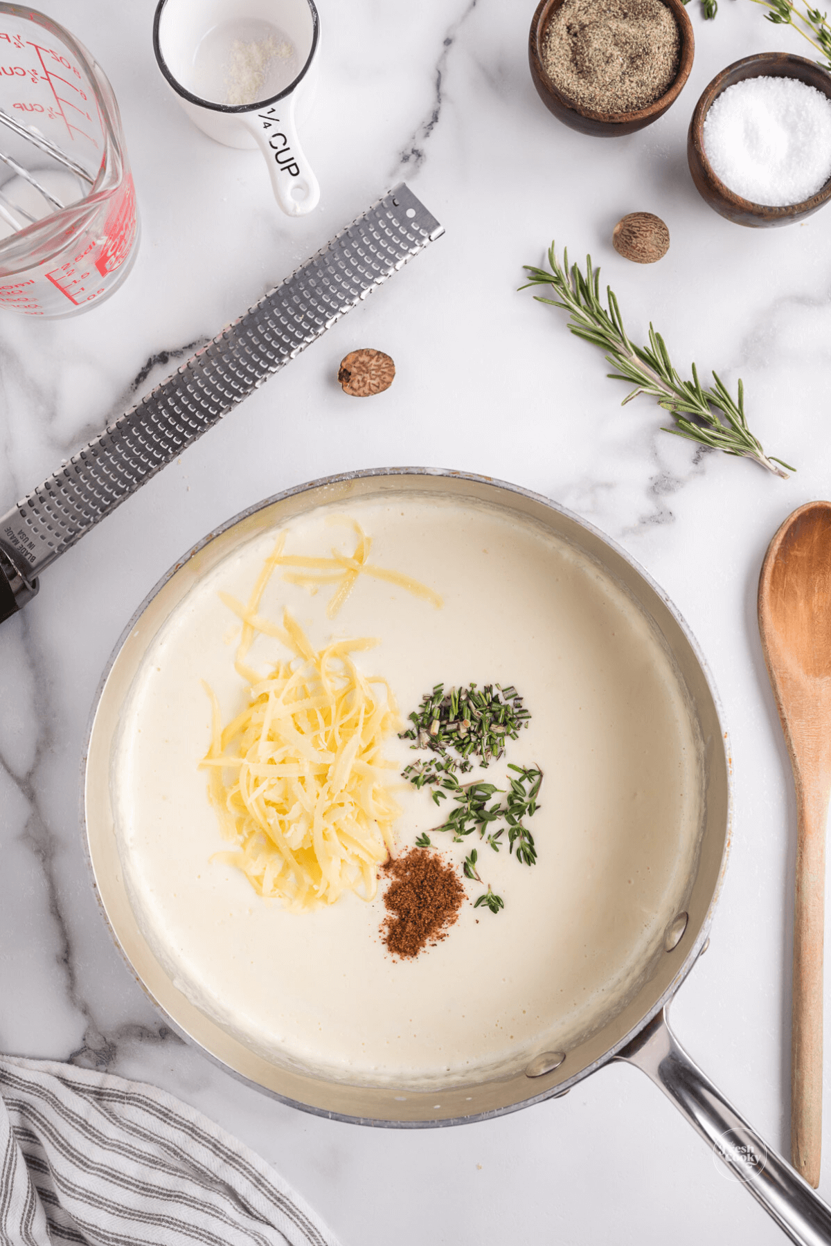 Adding spices, cheese to white sauce.