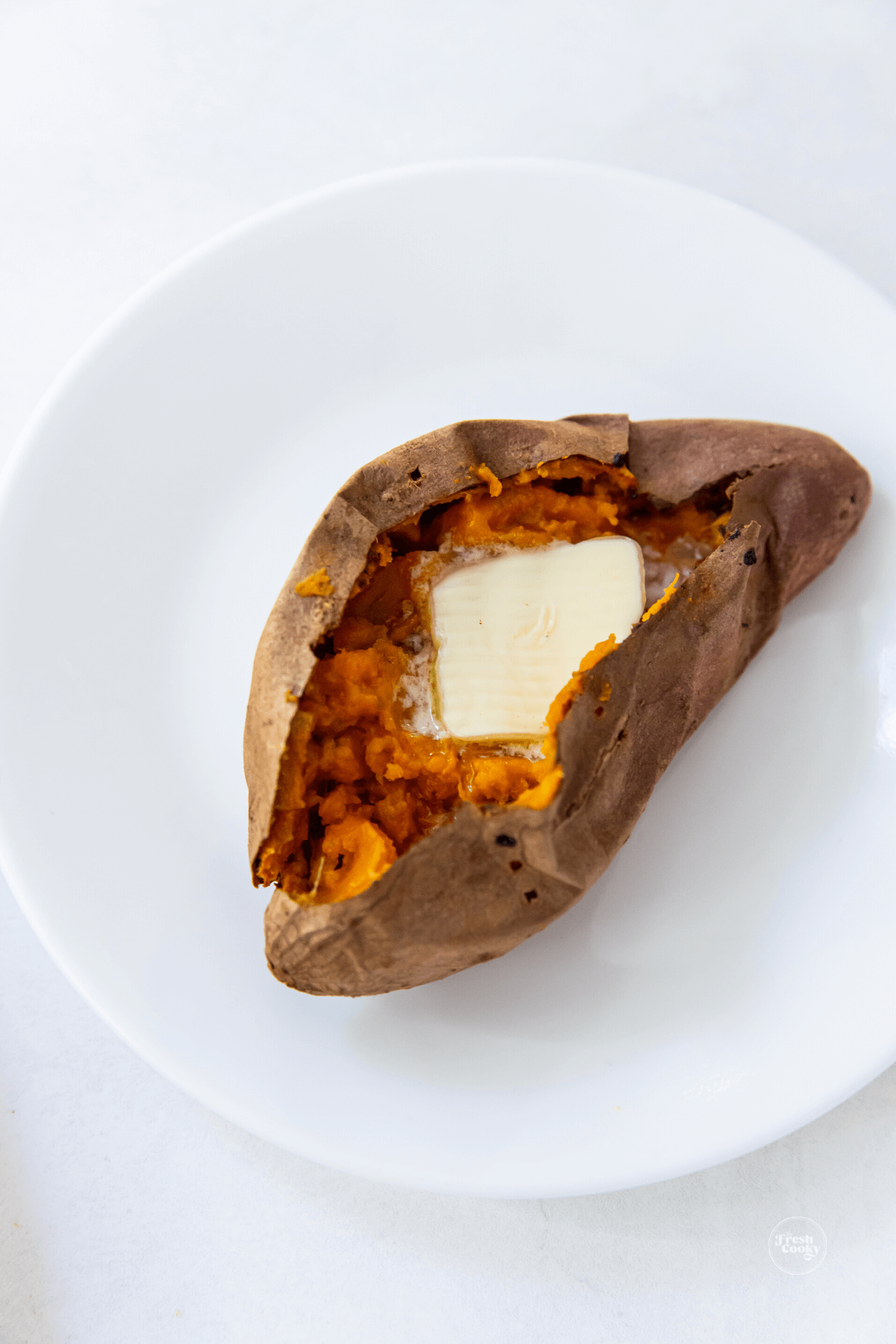 Sweet potato on plate with pat of butter.