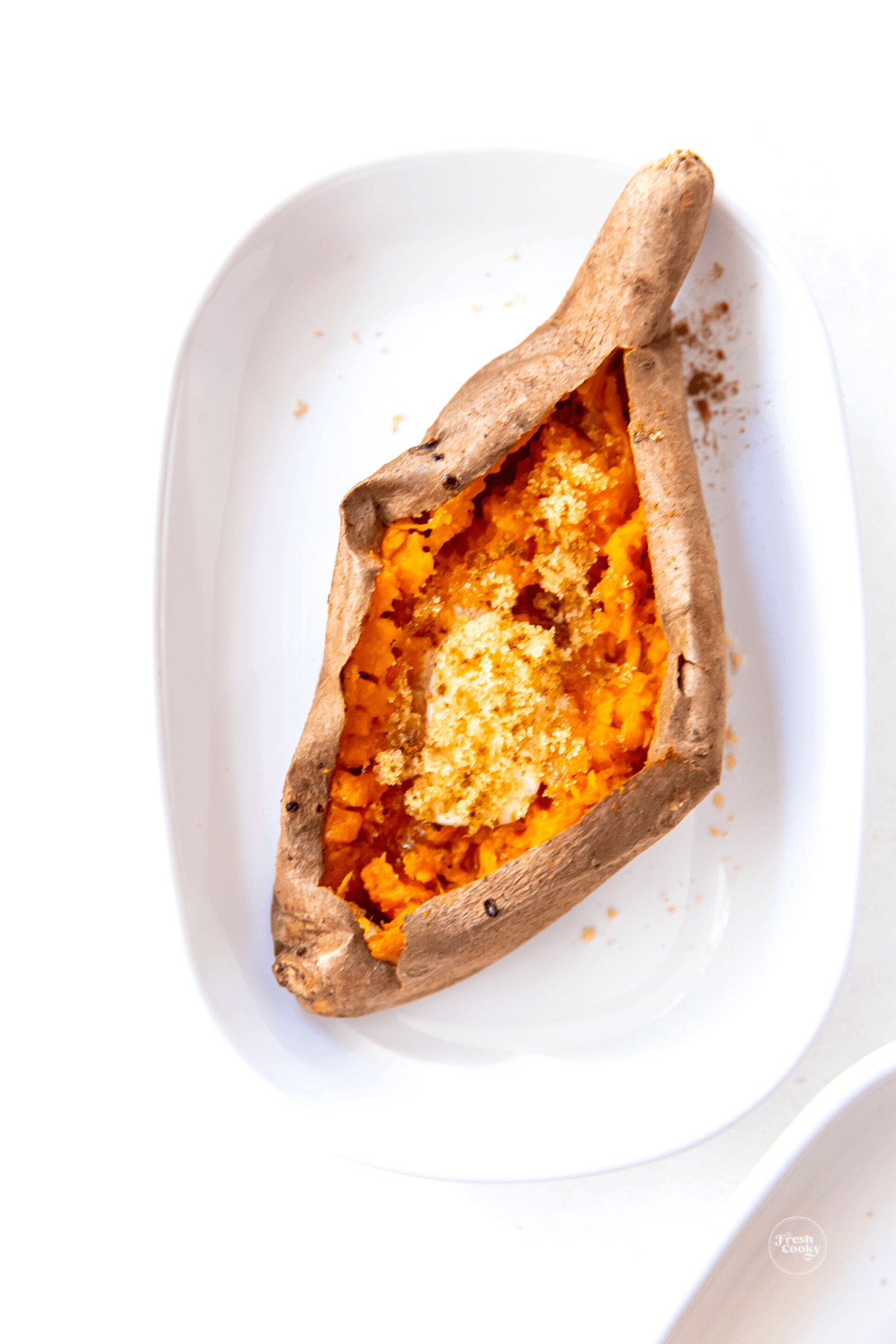 Sweet potato on plate with butter, cinnamon and brown sugar.