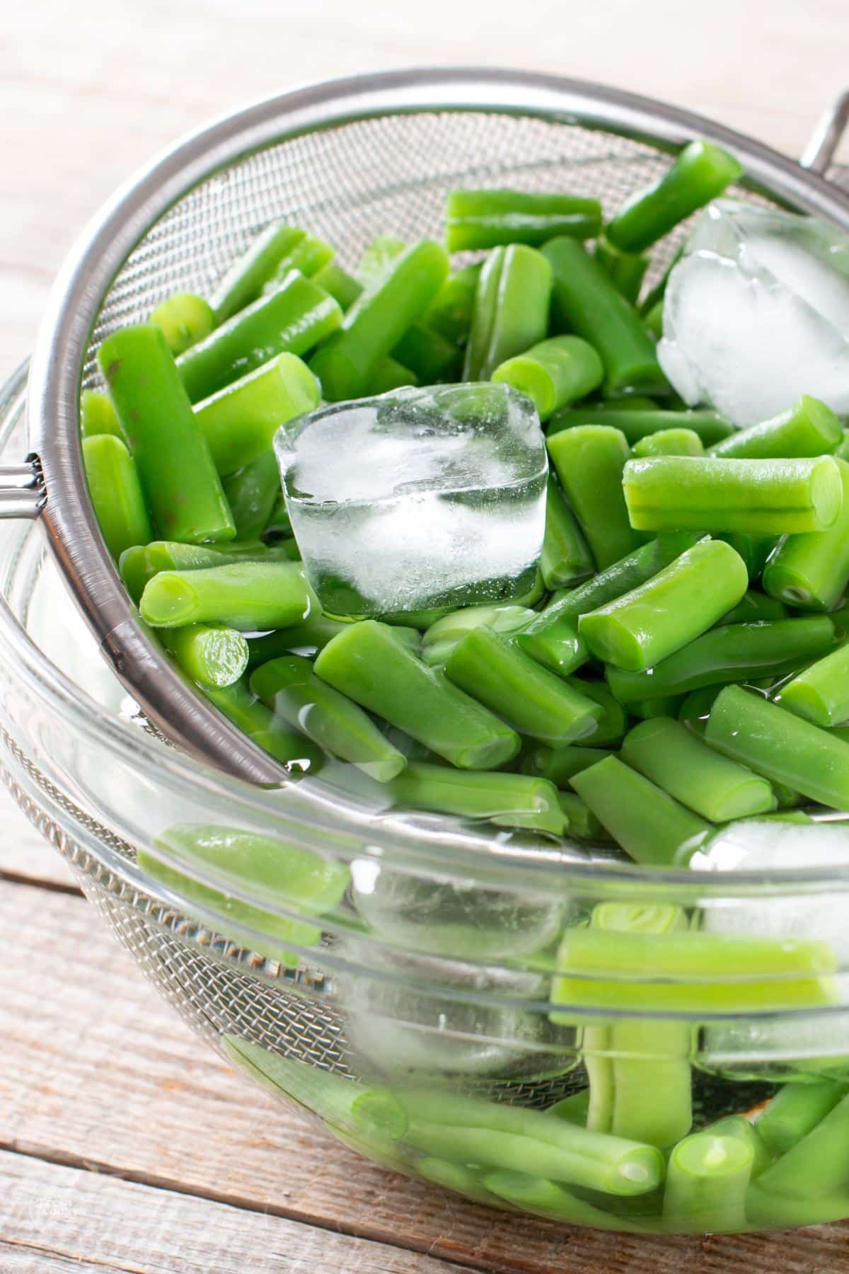 Blanched green beans in bowl of ice water.