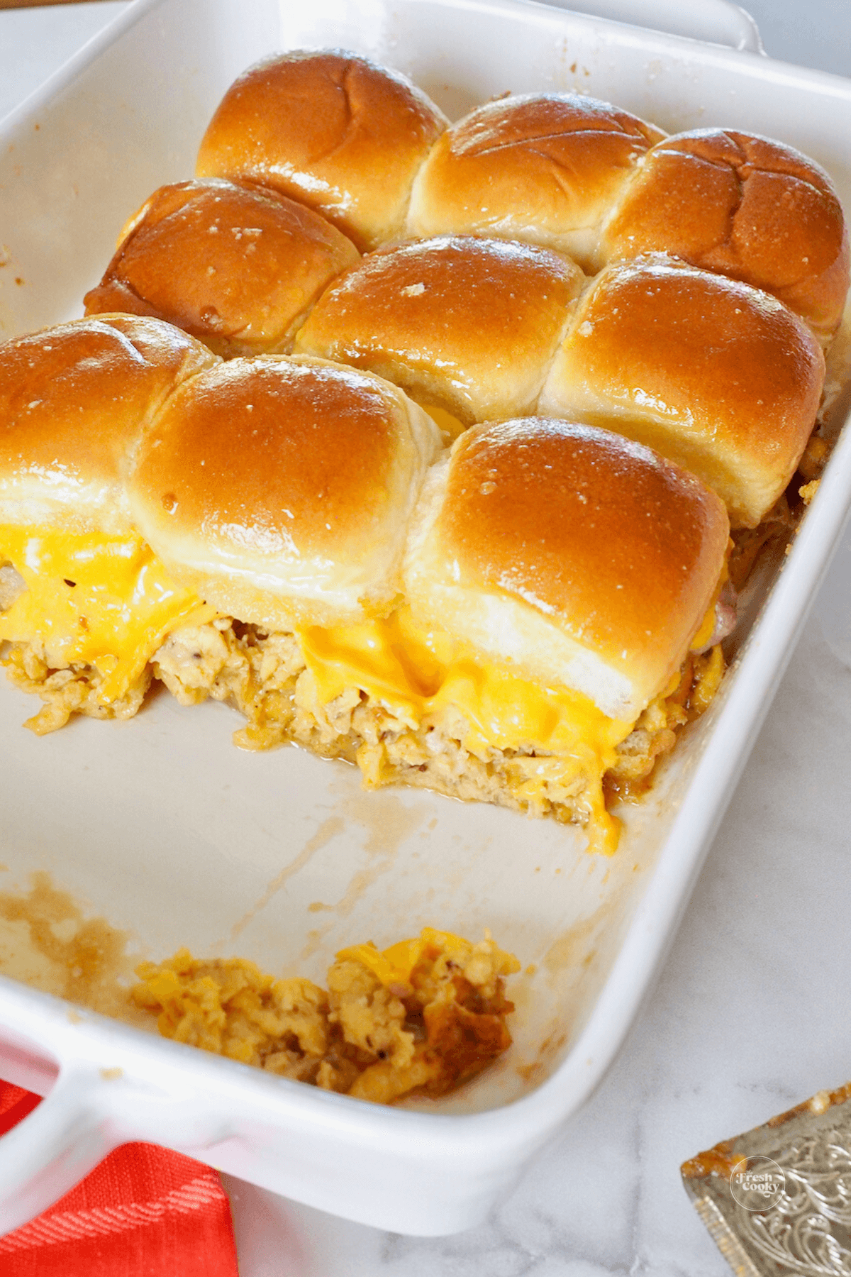 Baked sliders in pan with 3 of them removed.