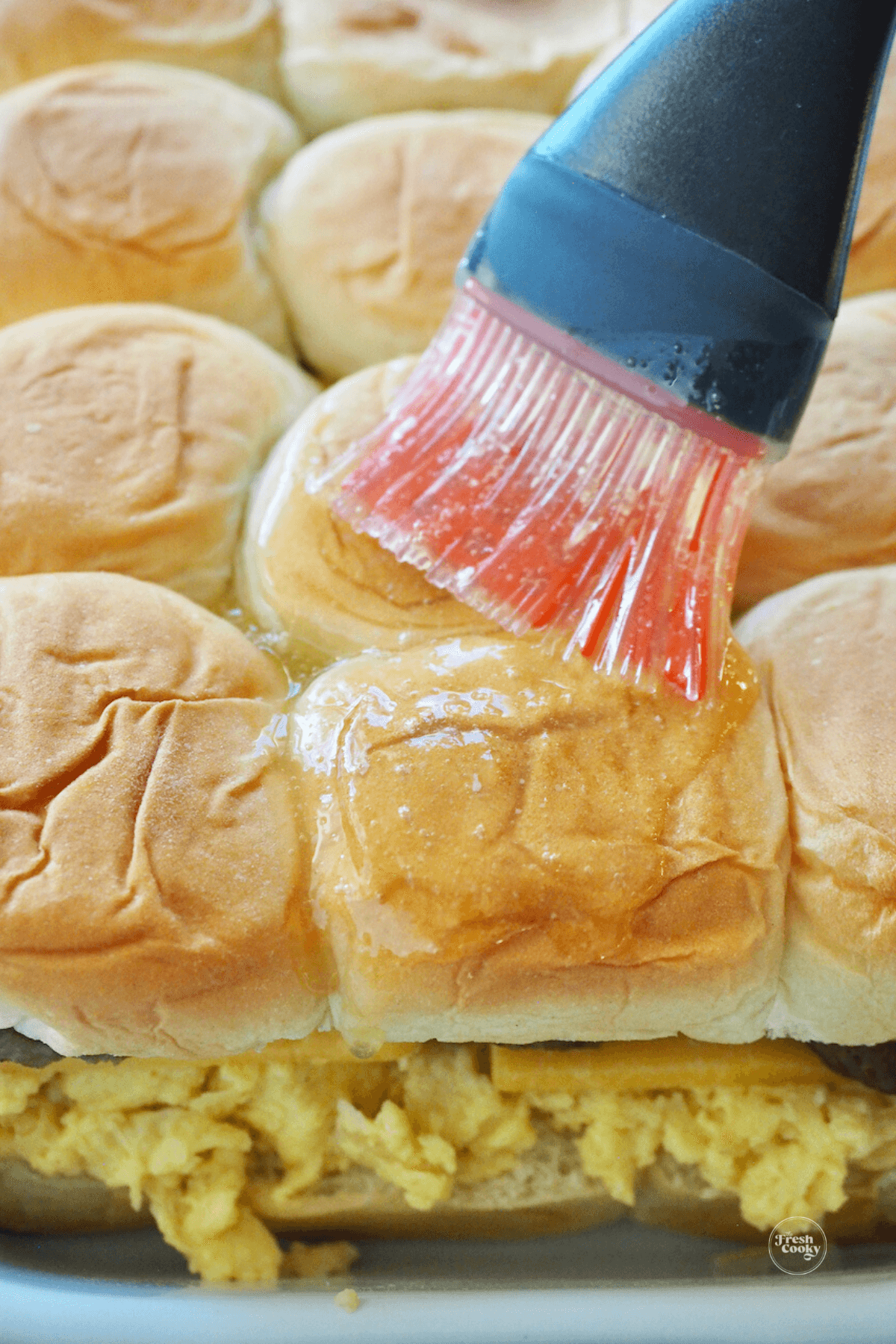 Brushing butter mixture on top and sides of rolls. 