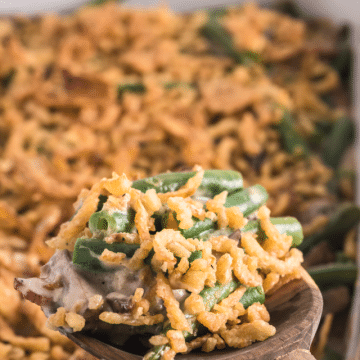 Green Bean Casserole with Bacon image with a wooden spoon taking out a hearty scoop.