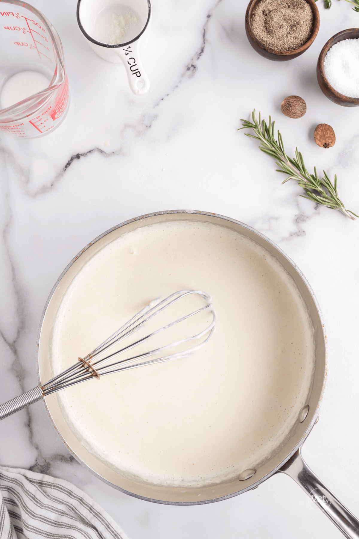 Whisking in milk to roux to make white bechamel sauce.