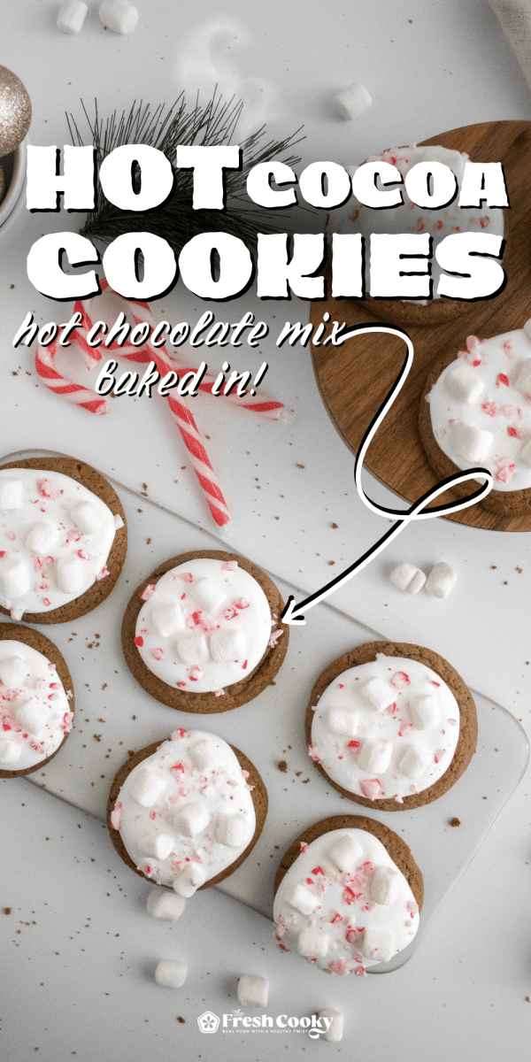 Several hot chocolate cookies on a tray topped with marshmallow fluff and crushed candy canes, for pinning.