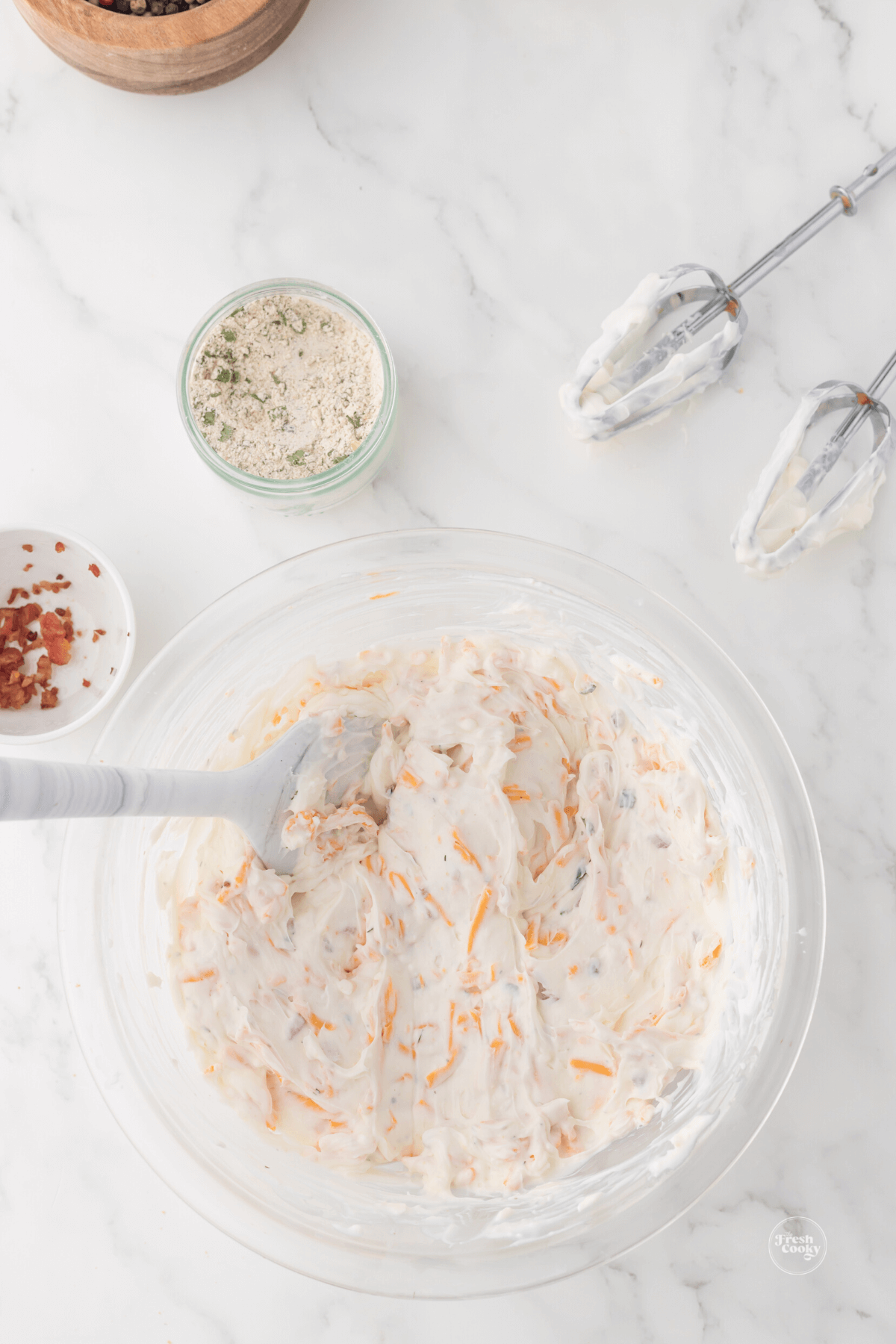 Mixing in cheeses and ranch dressing mix to cream cheese dip.