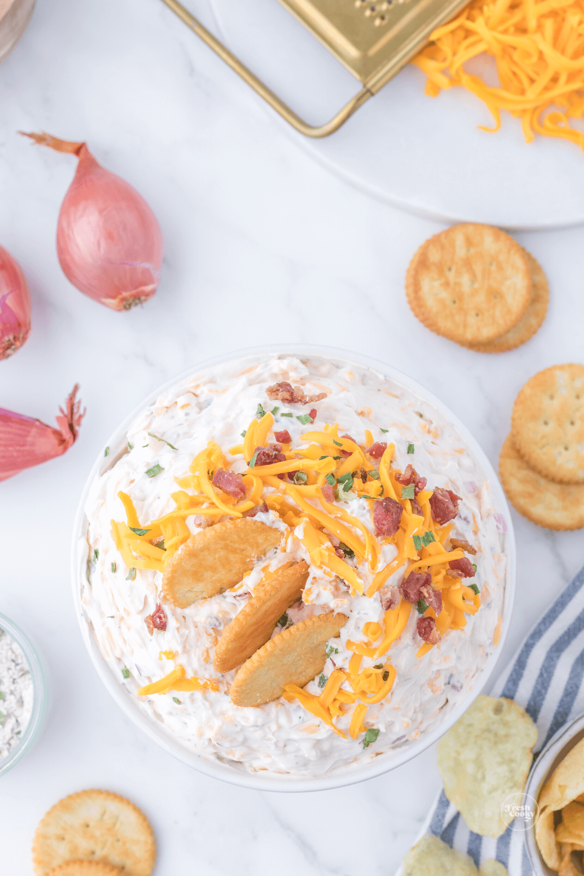 Cowboy crack dip with crackers in top, top down shot with shallots and crackers in background.