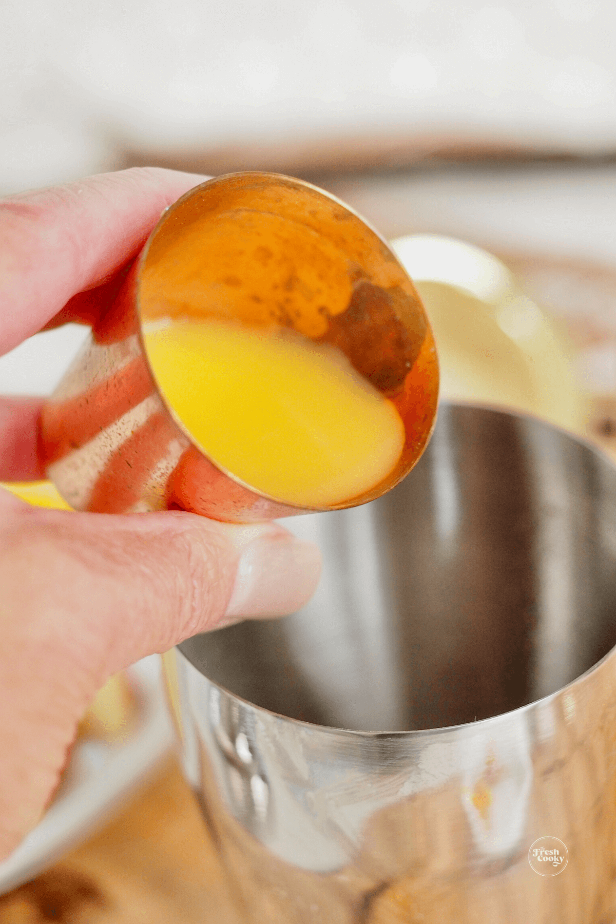 Pouring orange juice into the cocktail shaker. 